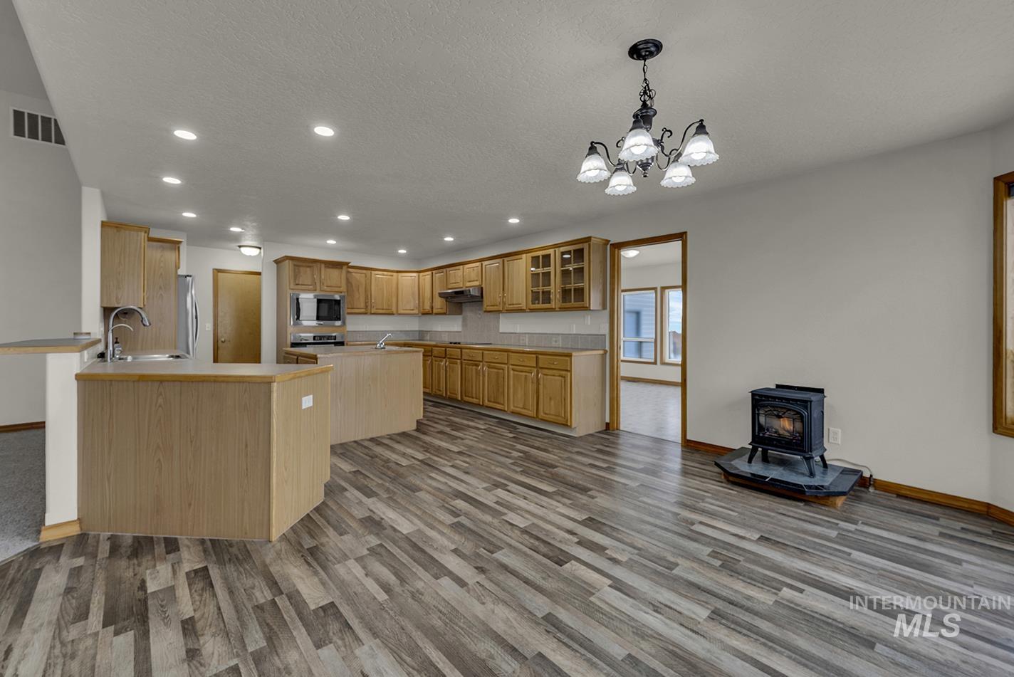 Kitchen with recessed lighting, a wood stove, pendant lighting, glass insert cabinets, and dark wood-style flooring