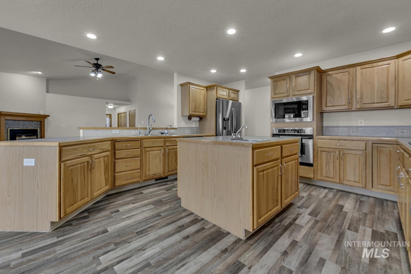 Kitchen with a peninsula, stainless steel appliances, light countertops, recessed lighting, and light wood-style floors