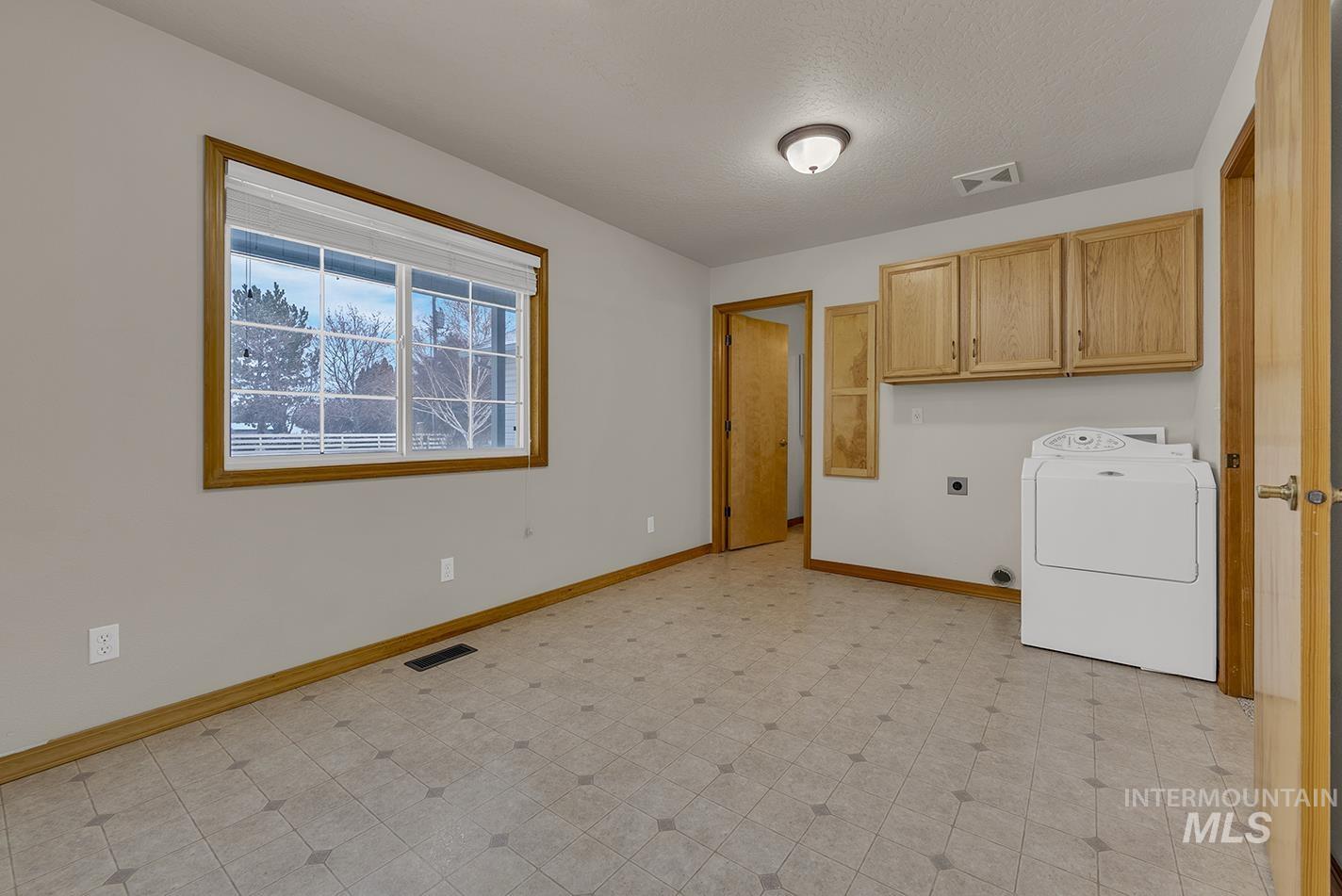 Laundry area featuring washer / dryer, light floors, cabinet space, and a textured ceiling