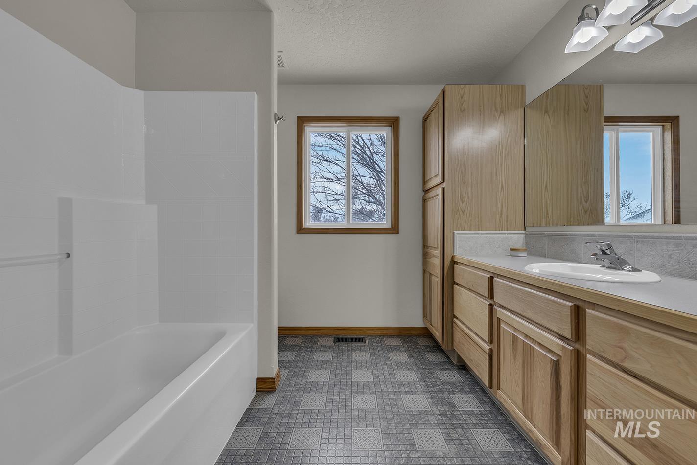 Full bathroom featuring vanity, shower / bath combination, a textured ceiling, and dark floors