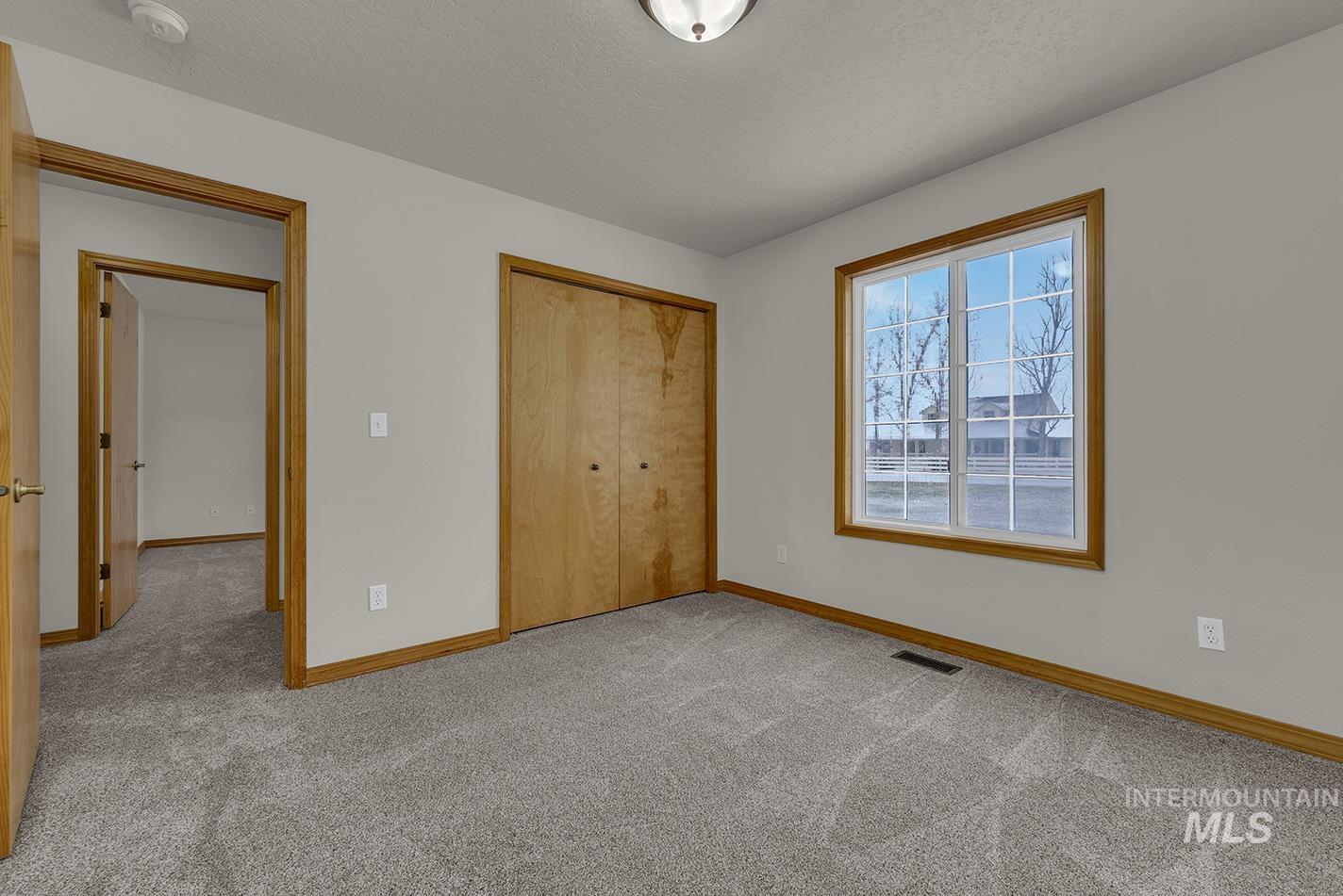 Unfurnished bedroom featuring light colored carpet, a closet, and a textured ceiling