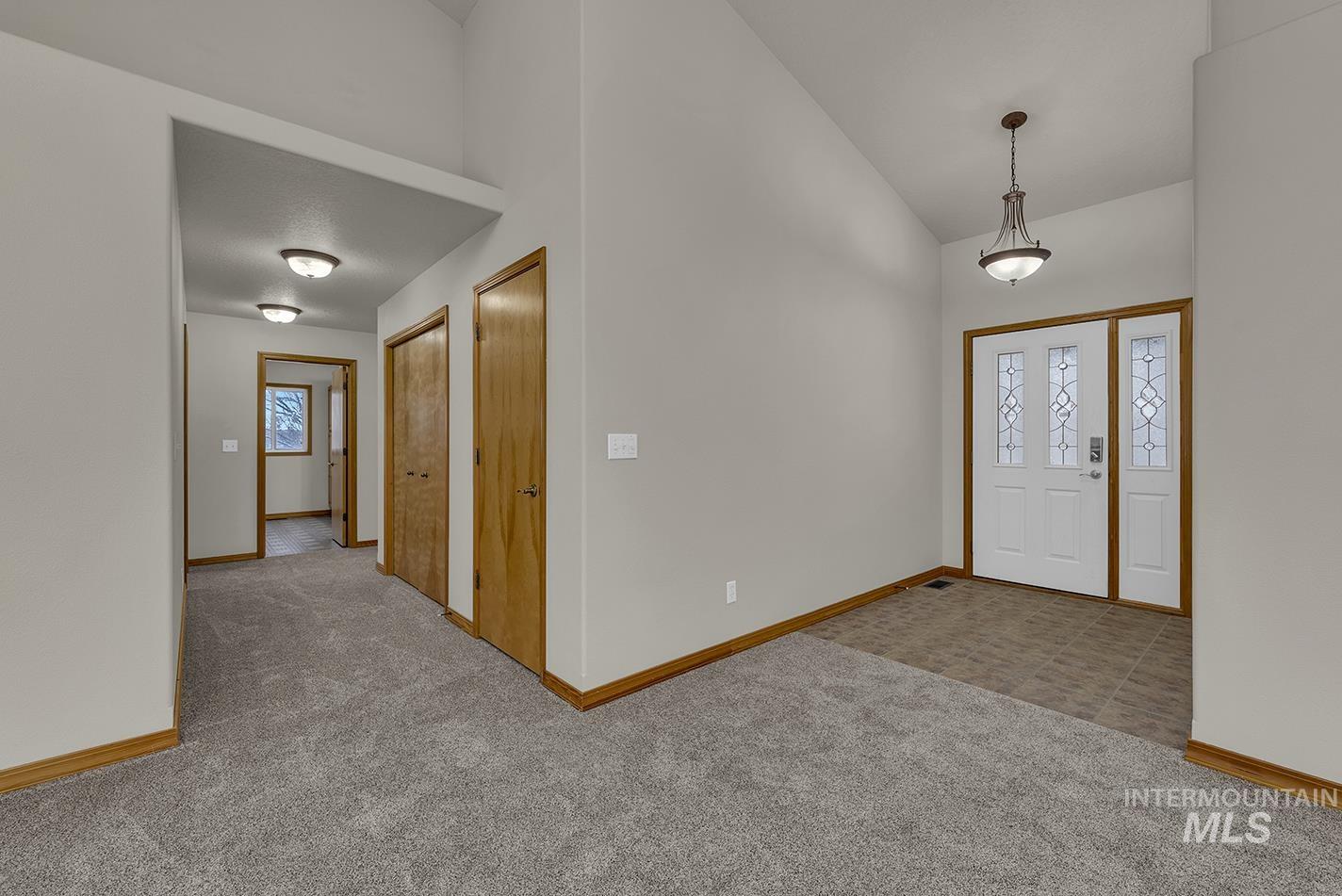 Foyer entrance with light carpet and high vaulted ceiling