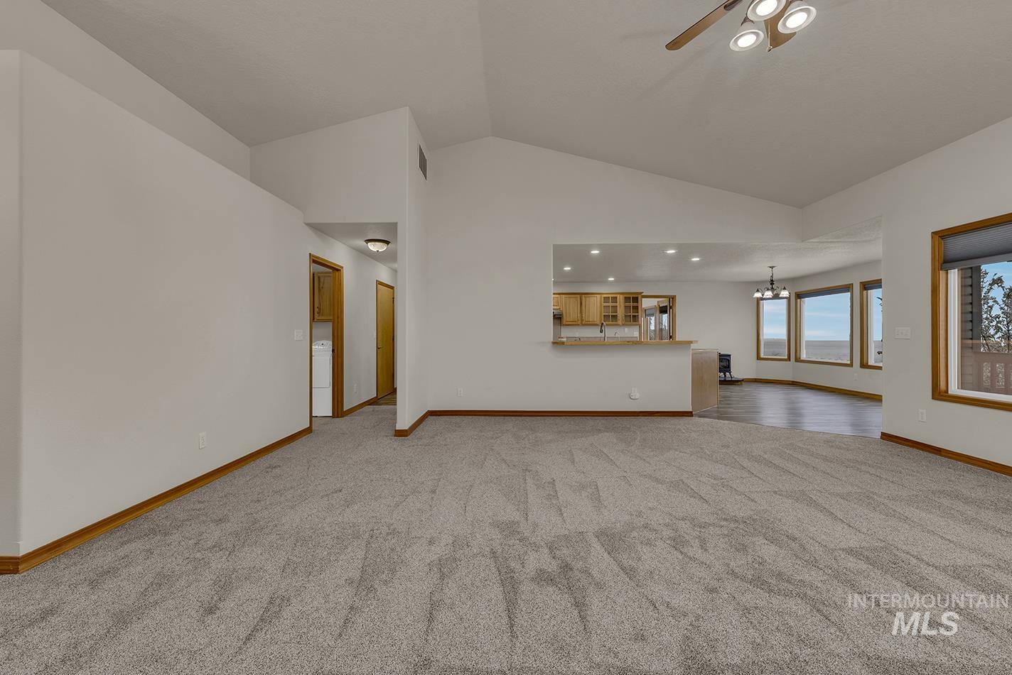 Unfurnished living room featuring carpet flooring, a chandelier, recessed lighting, ceiling fan, and high vaulted ceiling
