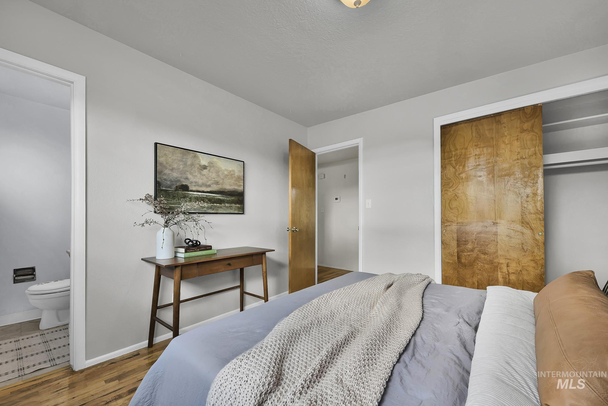 Bedroom with connected bathroom, a closet, and wood finished floors
