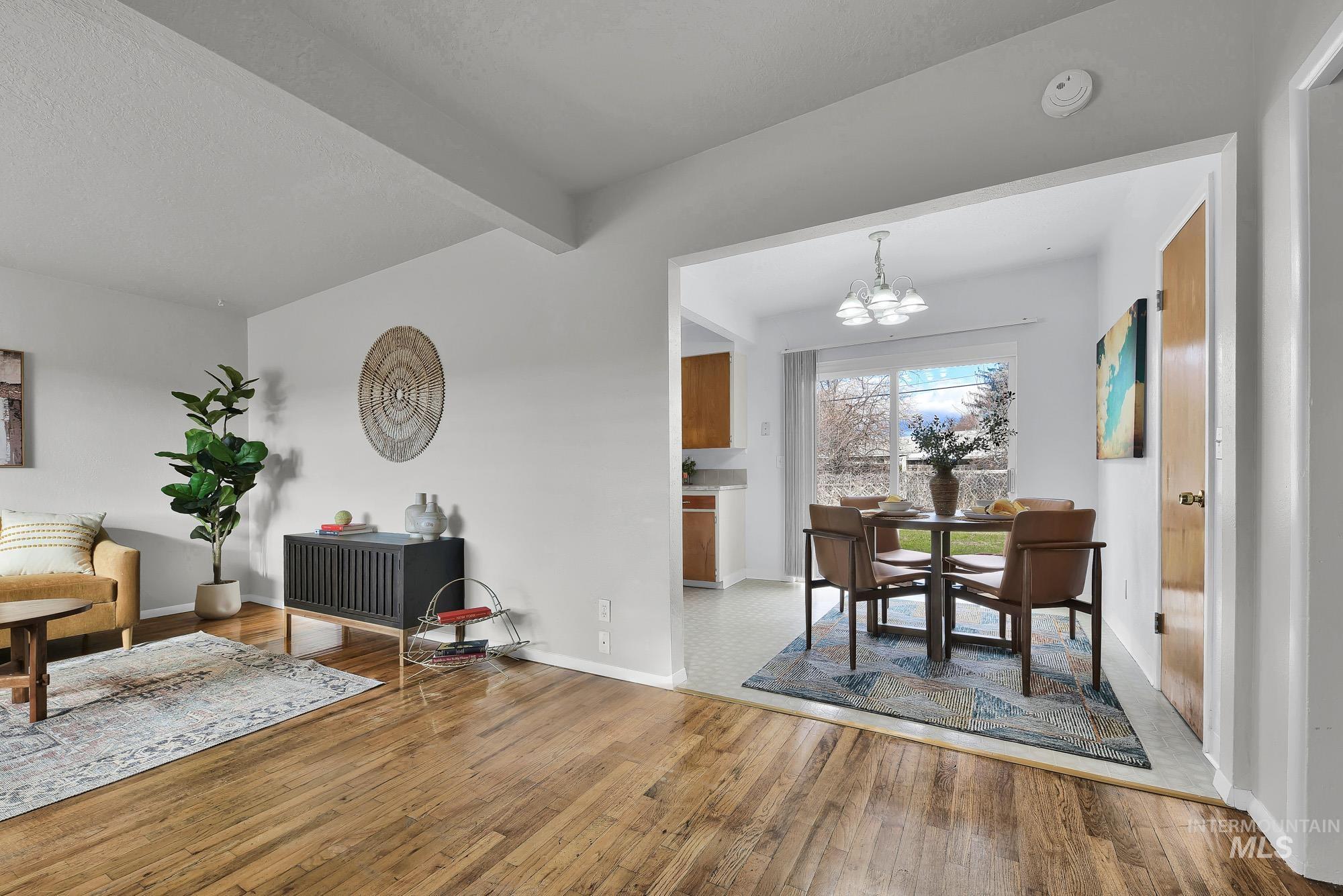 Dining room with beam ceiling, a chandelier, and hardwood / wood-style flooring