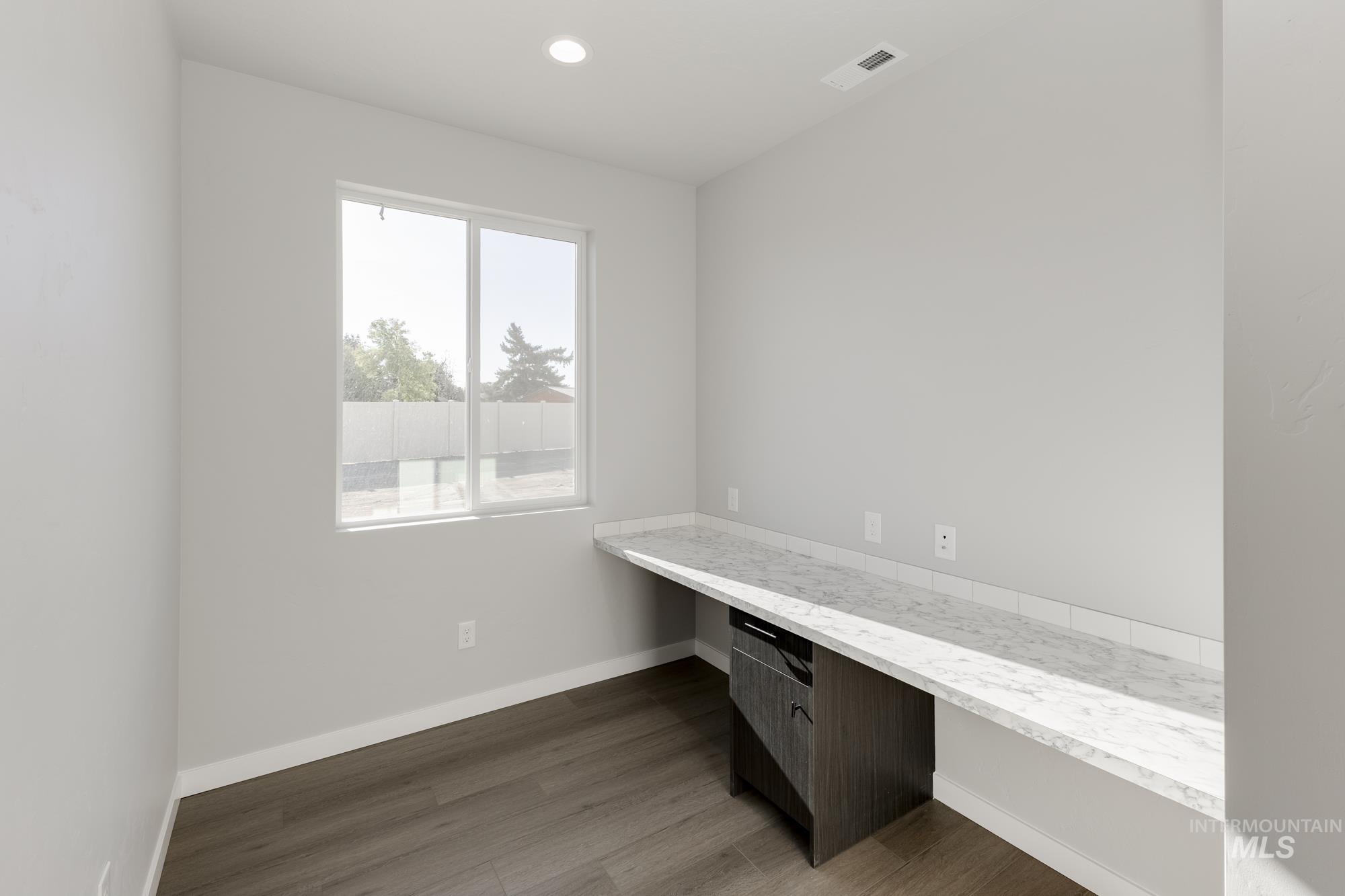 Unfurnished office with built in desk, dark wood-style flooring, and recessed lighting