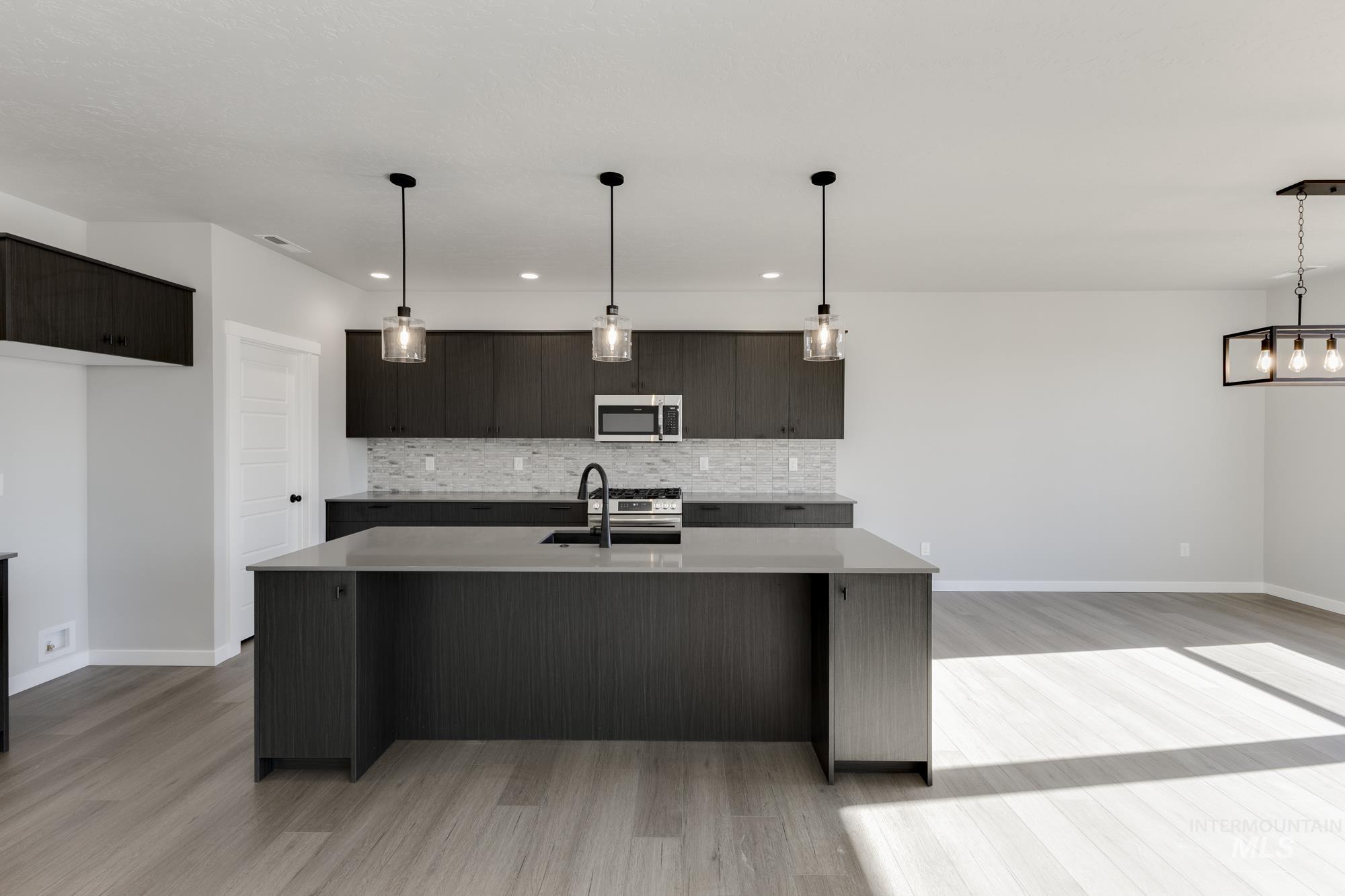 Kitchen featuring decorative light fixtures, an island with sink, modern cabinets, stainless steel appliances, and recessed lighting
