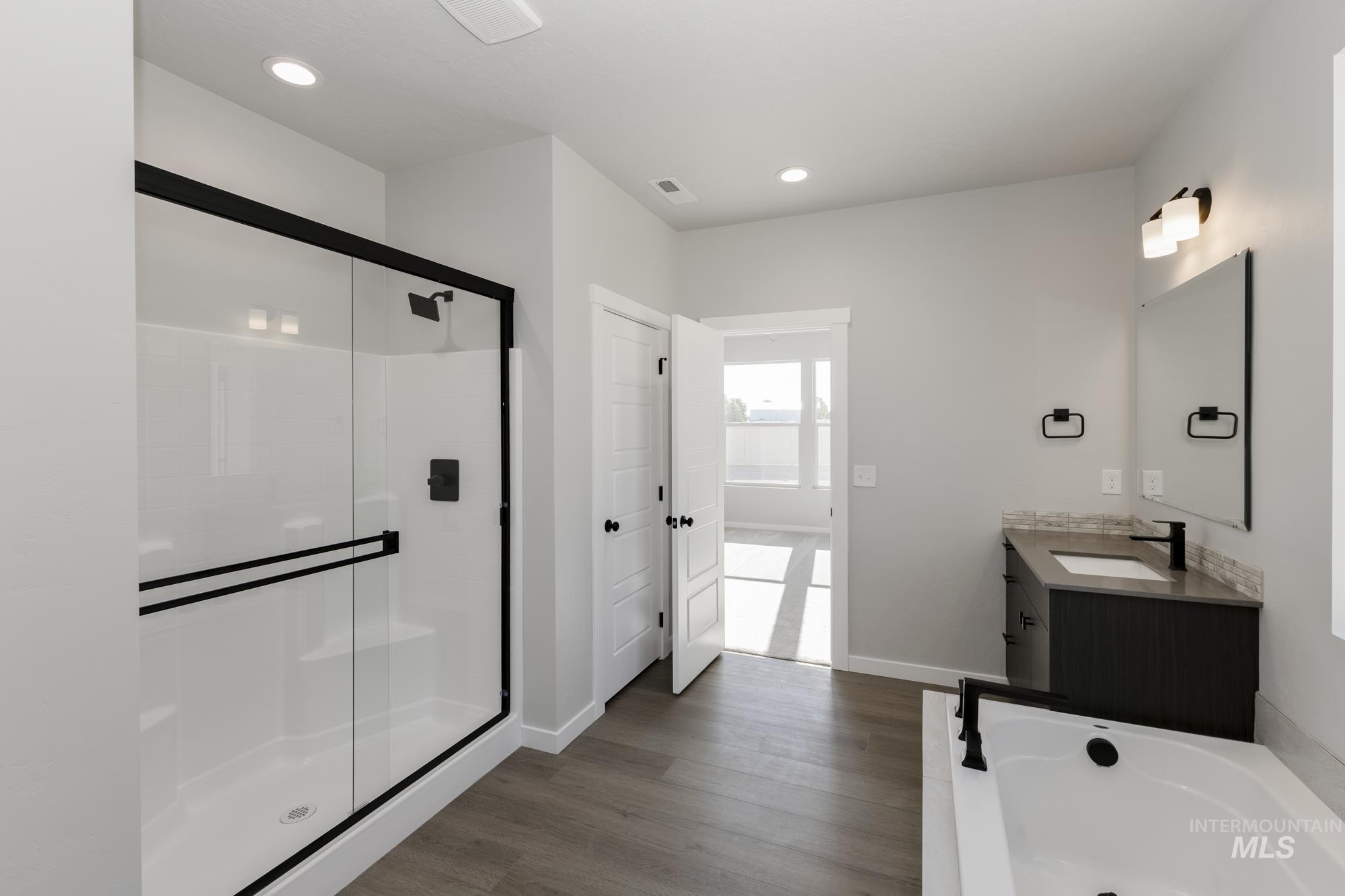 Bathroom featuring vanity, a garden tub, a stall shower, dark wood-style floors, and recessed lighting