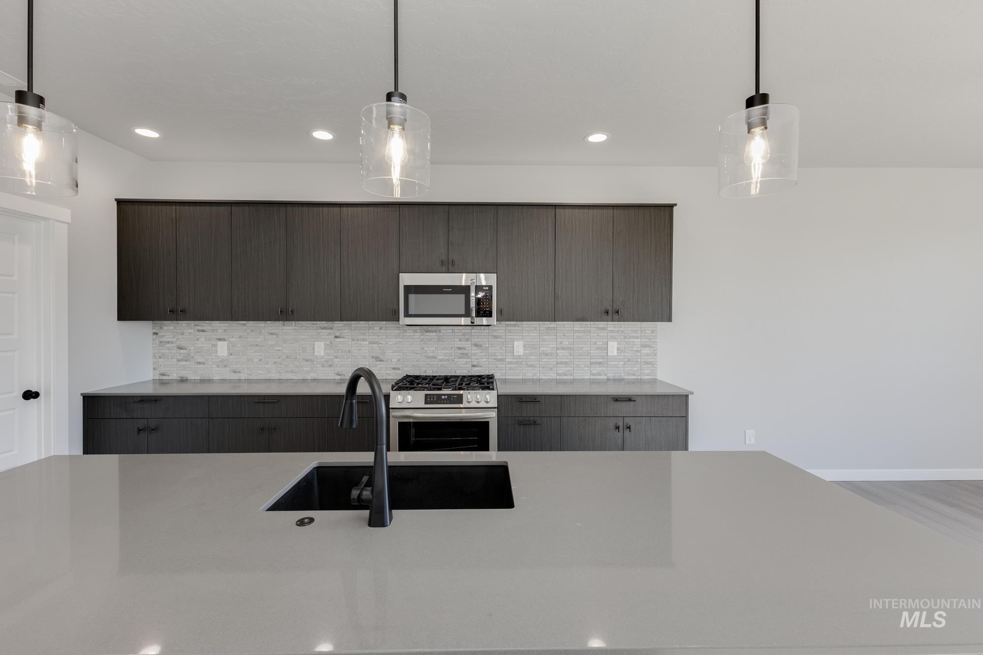 Kitchen featuring decorative light fixtures, stainless steel appliances, modern cabinets, decorative backsplash, and recessed lighting
