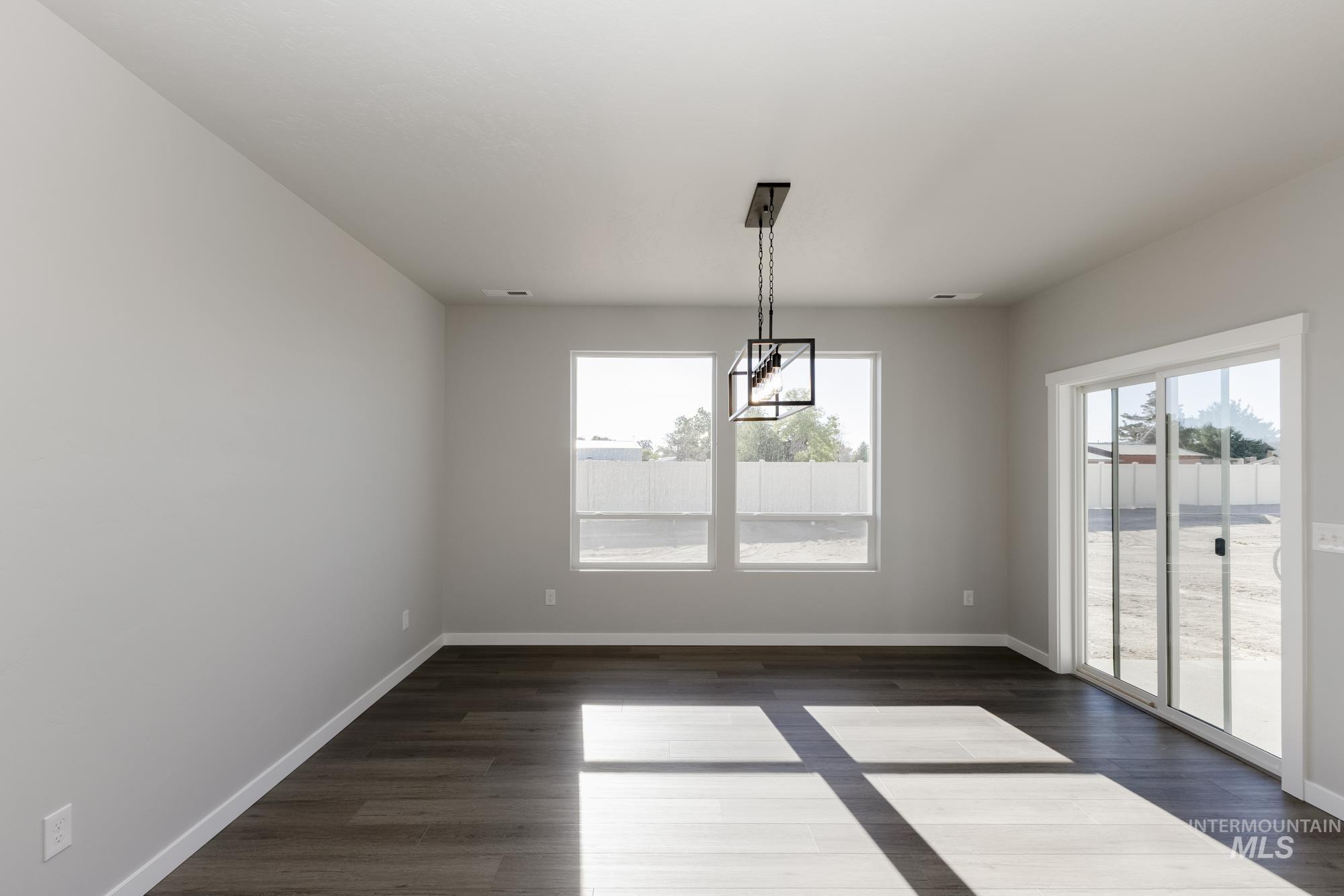 Unfurnished dining area with dark wood-type flooring and baseboards