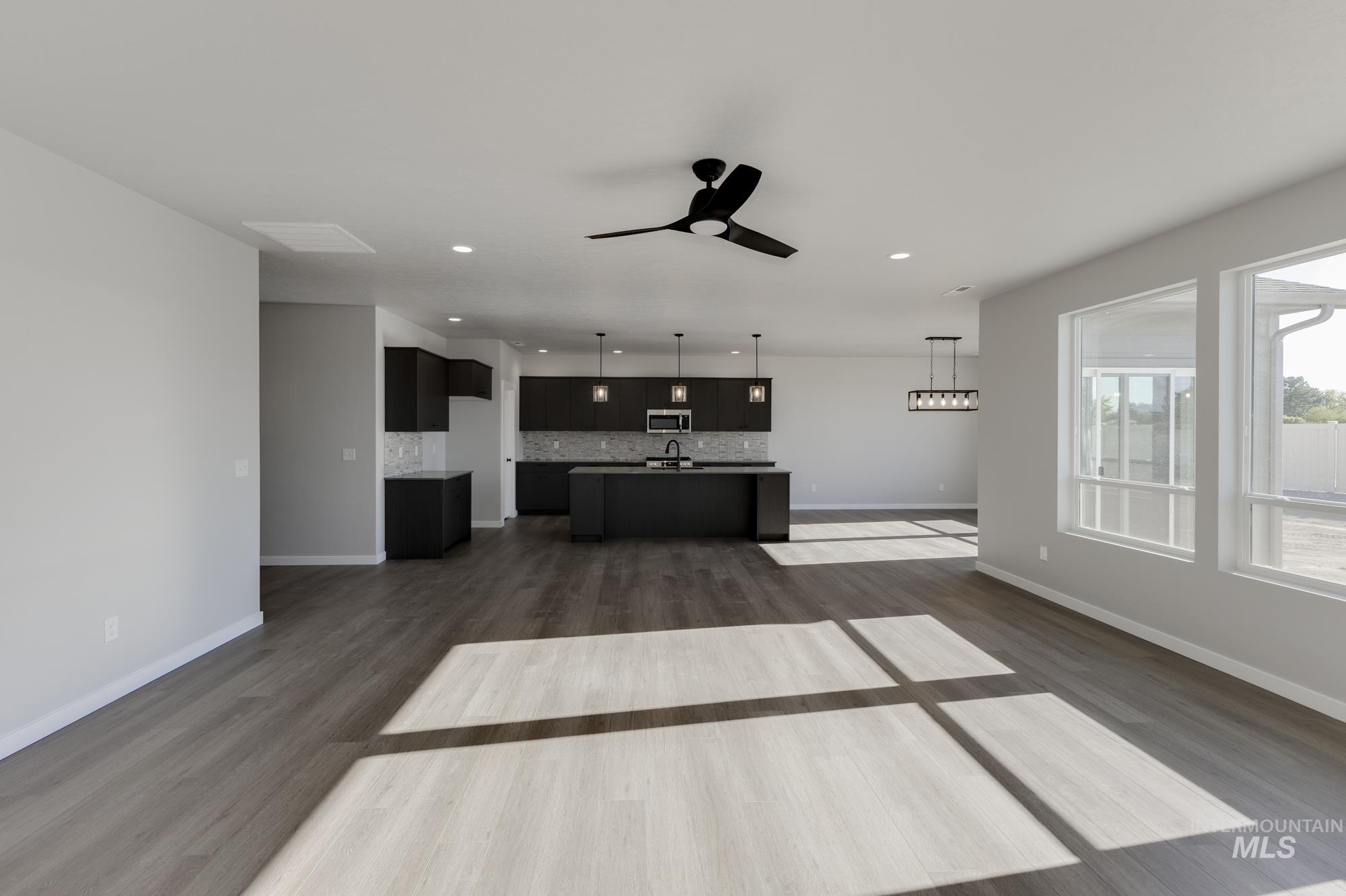 Unfurnished living room featuring ceiling fan, recessed lighting, and dark wood-style floors