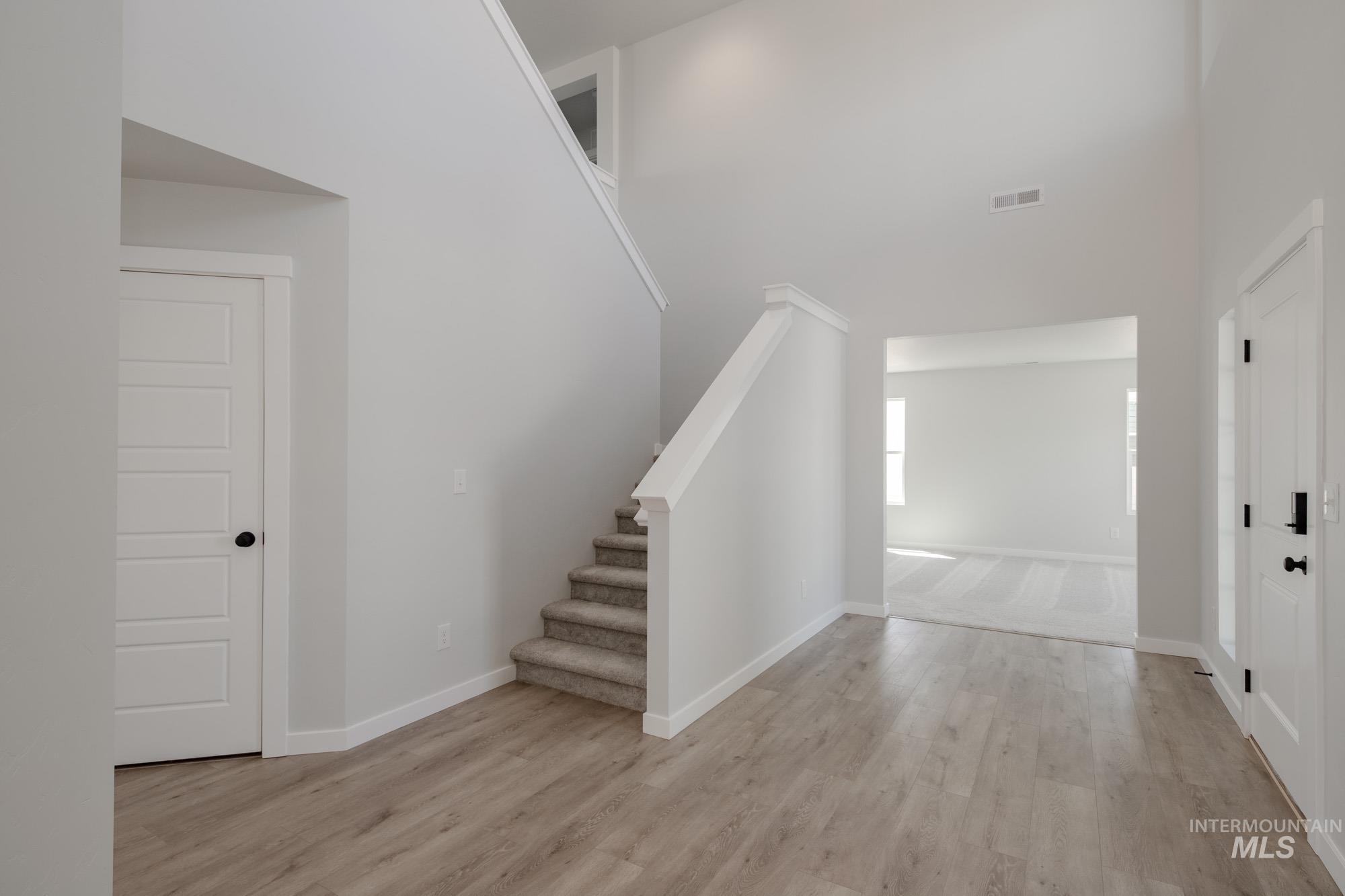 Foyer entrance featuring stairs, light wood-type flooring, and a towering ceiling