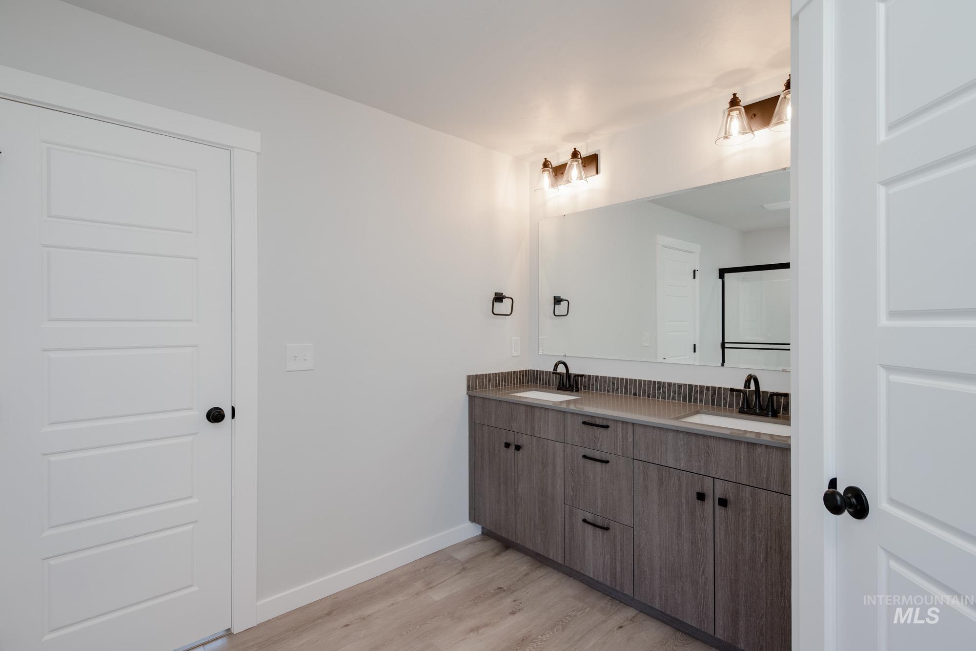 Bathroom featuring double vanity and light wood finished floors
