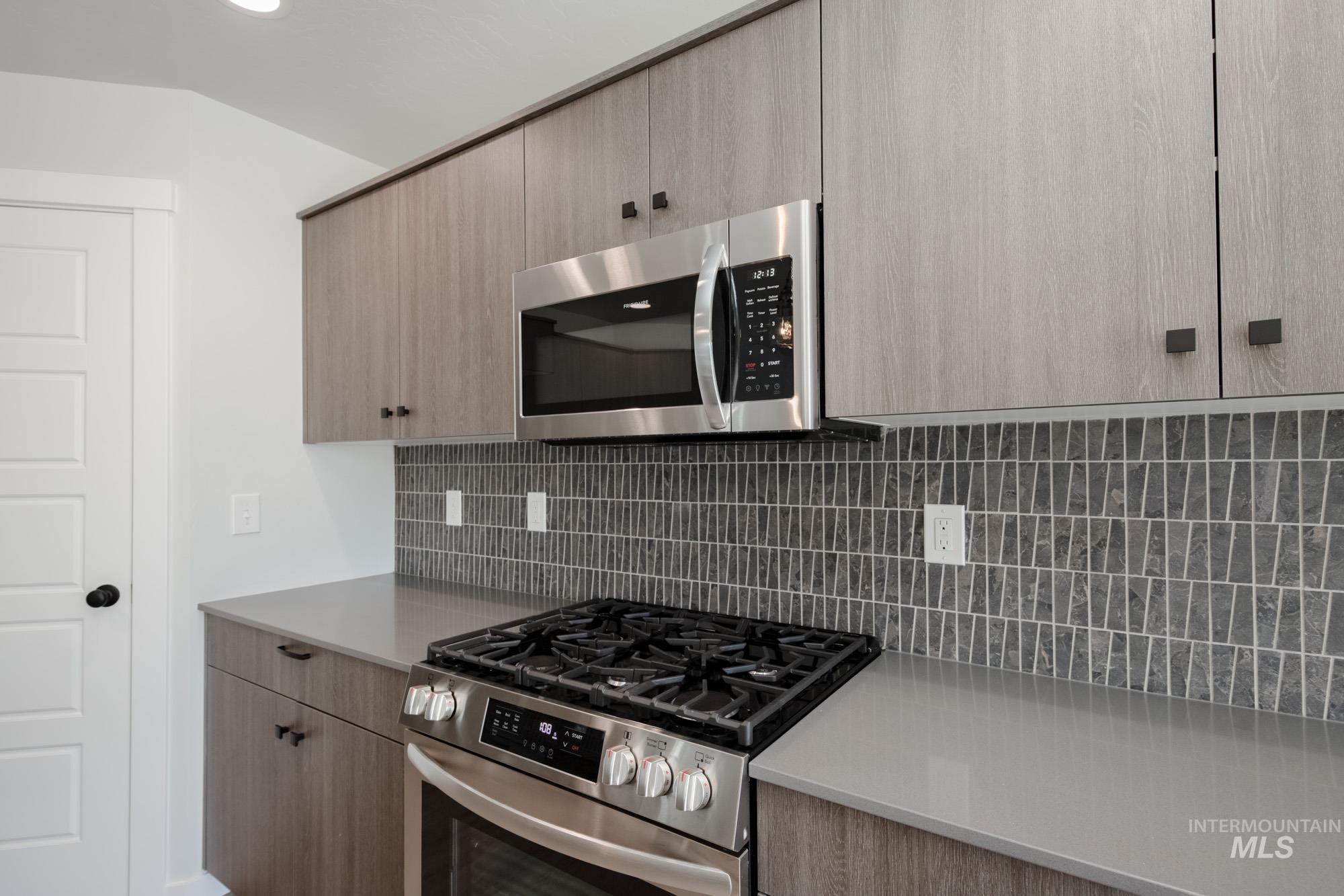 Kitchen featuring appliances with stainless steel finishes, backsplash, modern cabinets, and light brown cabinetry