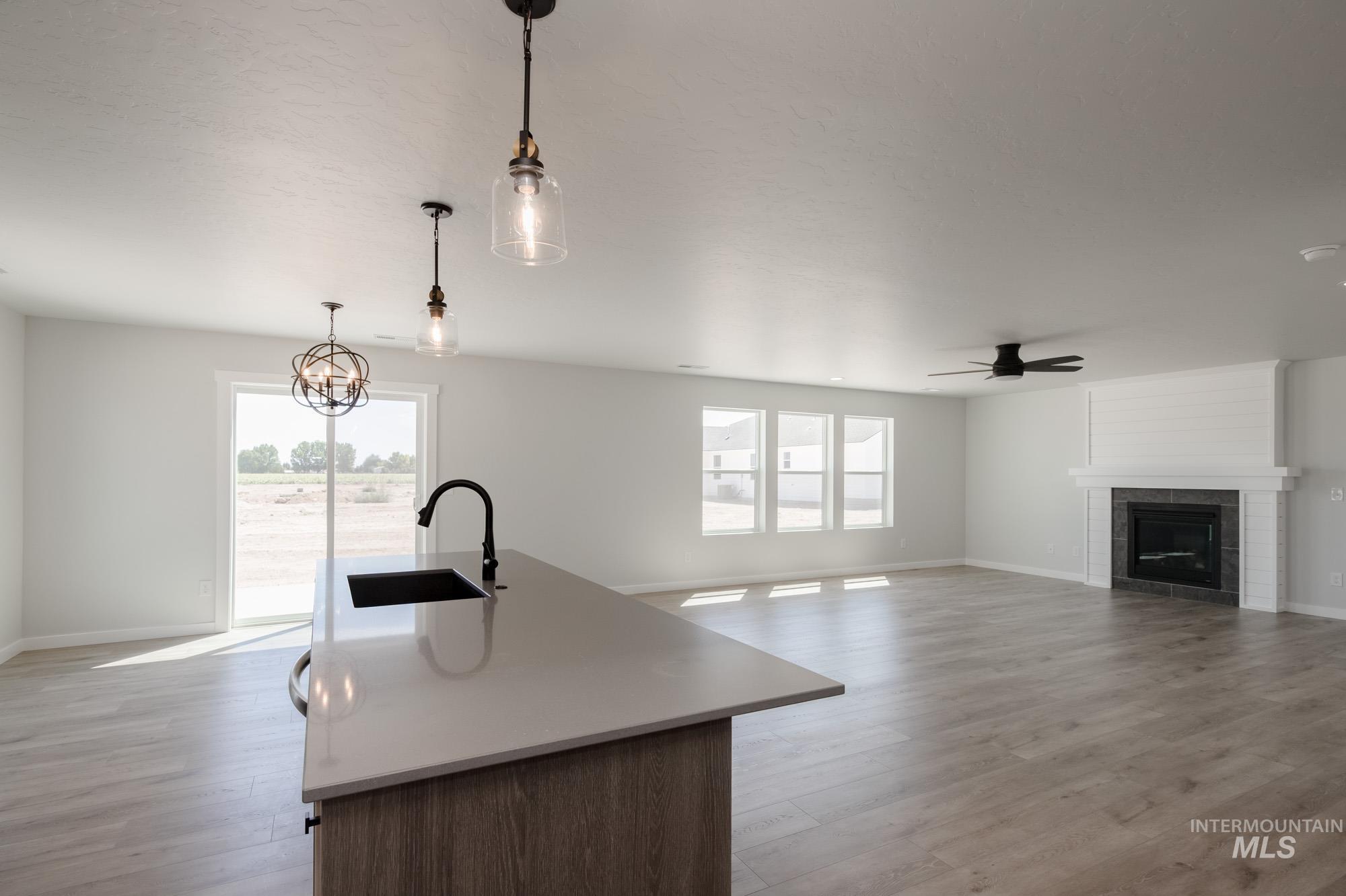 Kitchen featuring open floor plan, pendant lighting, an island with sink, a fireplace, and healthy amount of natural light