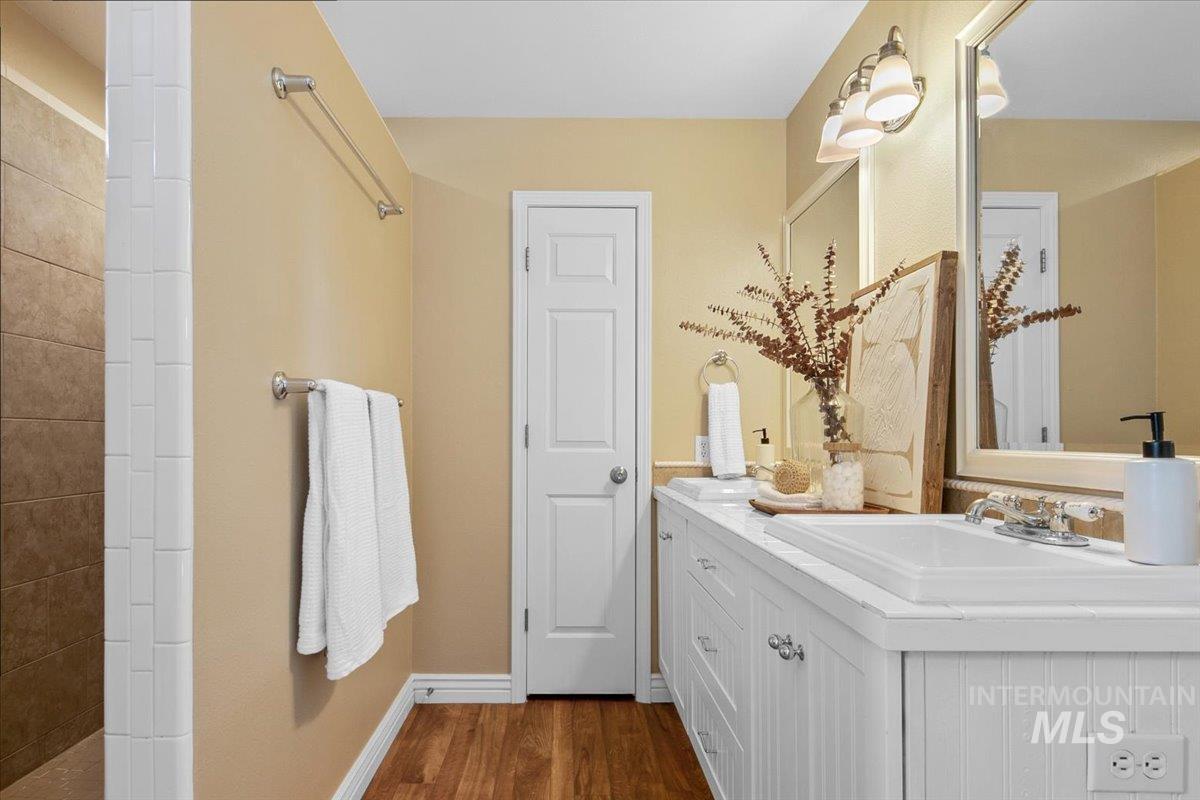 Full bathroom with dark wood-style flooring and vanity