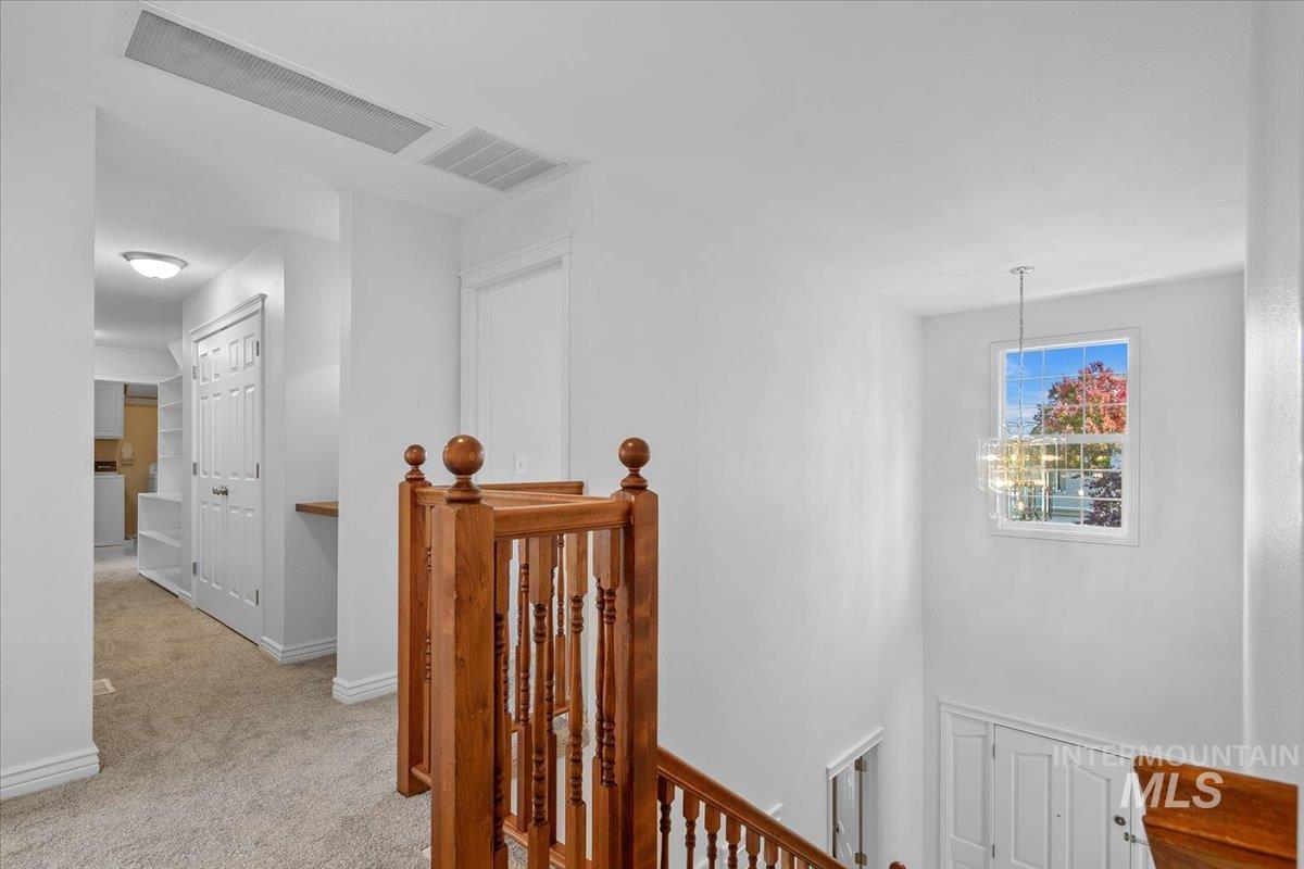 Corridor featuring an upstairs landing and light colored carpet
