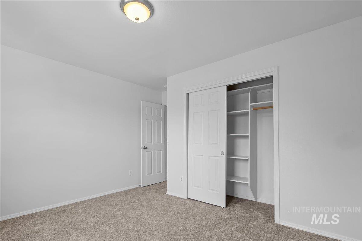 Unfurnished bedroom featuring light carpet and a closet