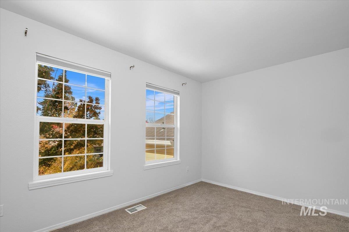 Carpeted spare room featuring baseboards