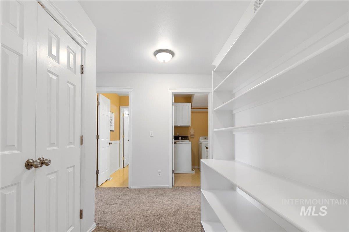 Corridor featuring light colored carpet and baseboards