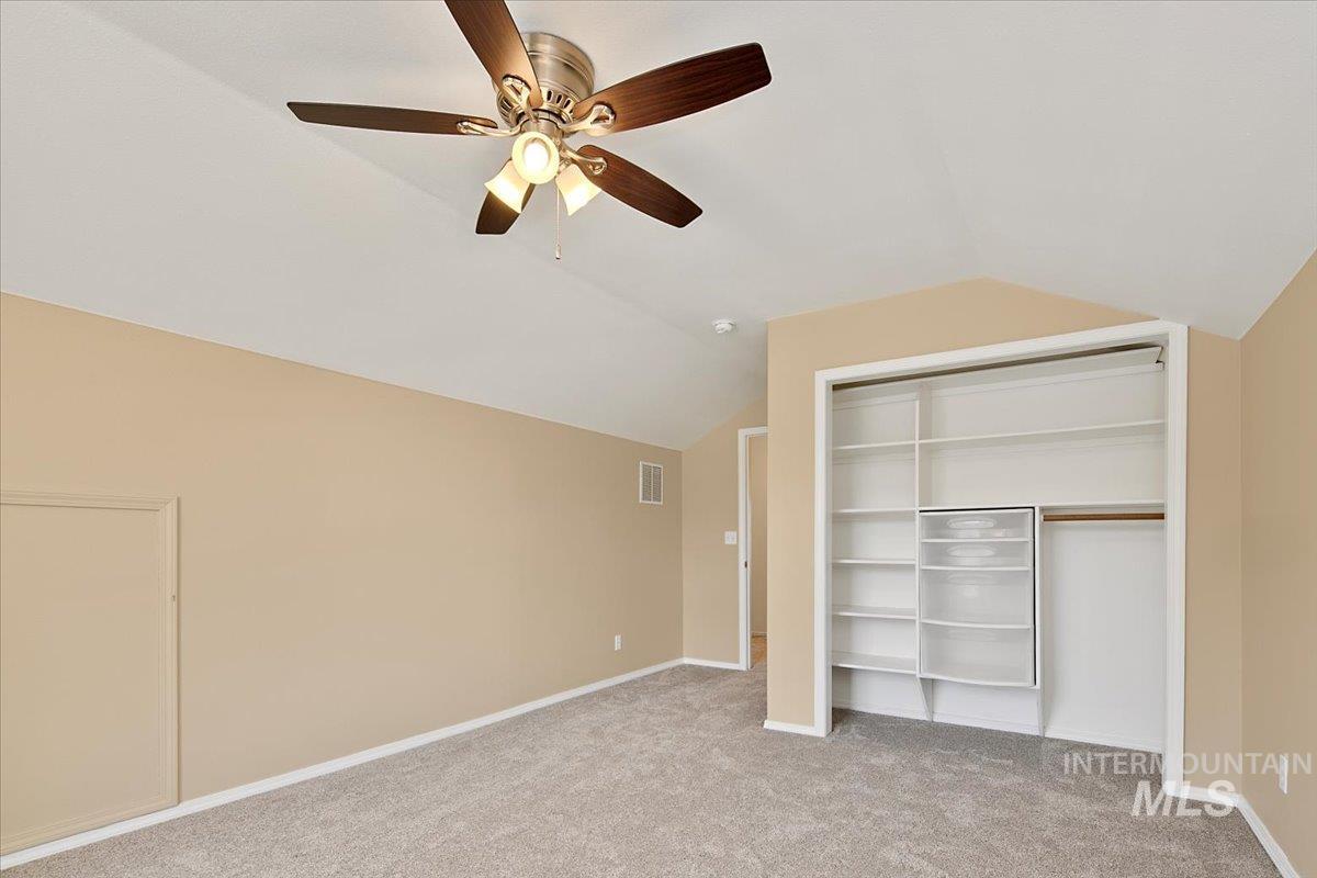 Unfurnished bedroom with lofted ceiling, light carpet, a closet, and ceiling fan