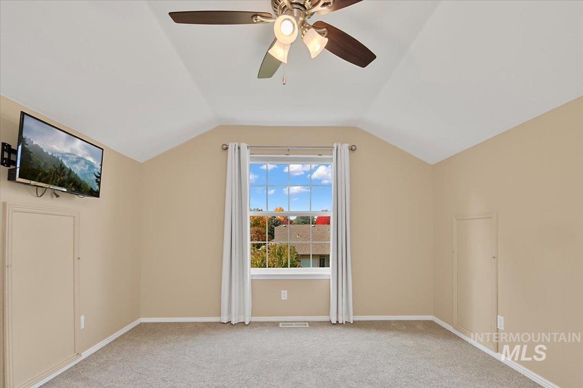 Bonus room with light carpet, lofted ceiling, and a ceiling fan