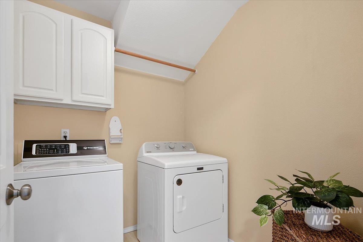 Laundry room featuring cabinet space, washing machine and clothes dryer, and vaulted ceiling