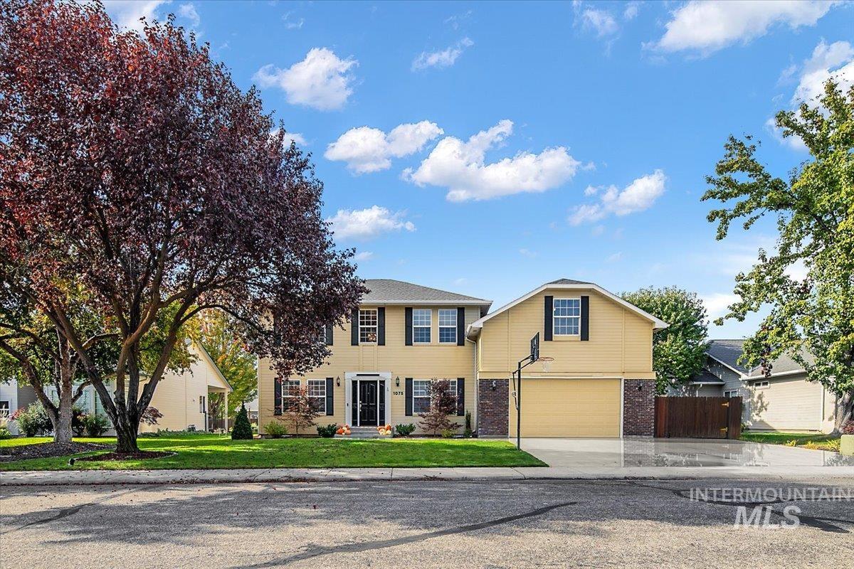 Colonial home featuring brick siding, driveway, and a garage