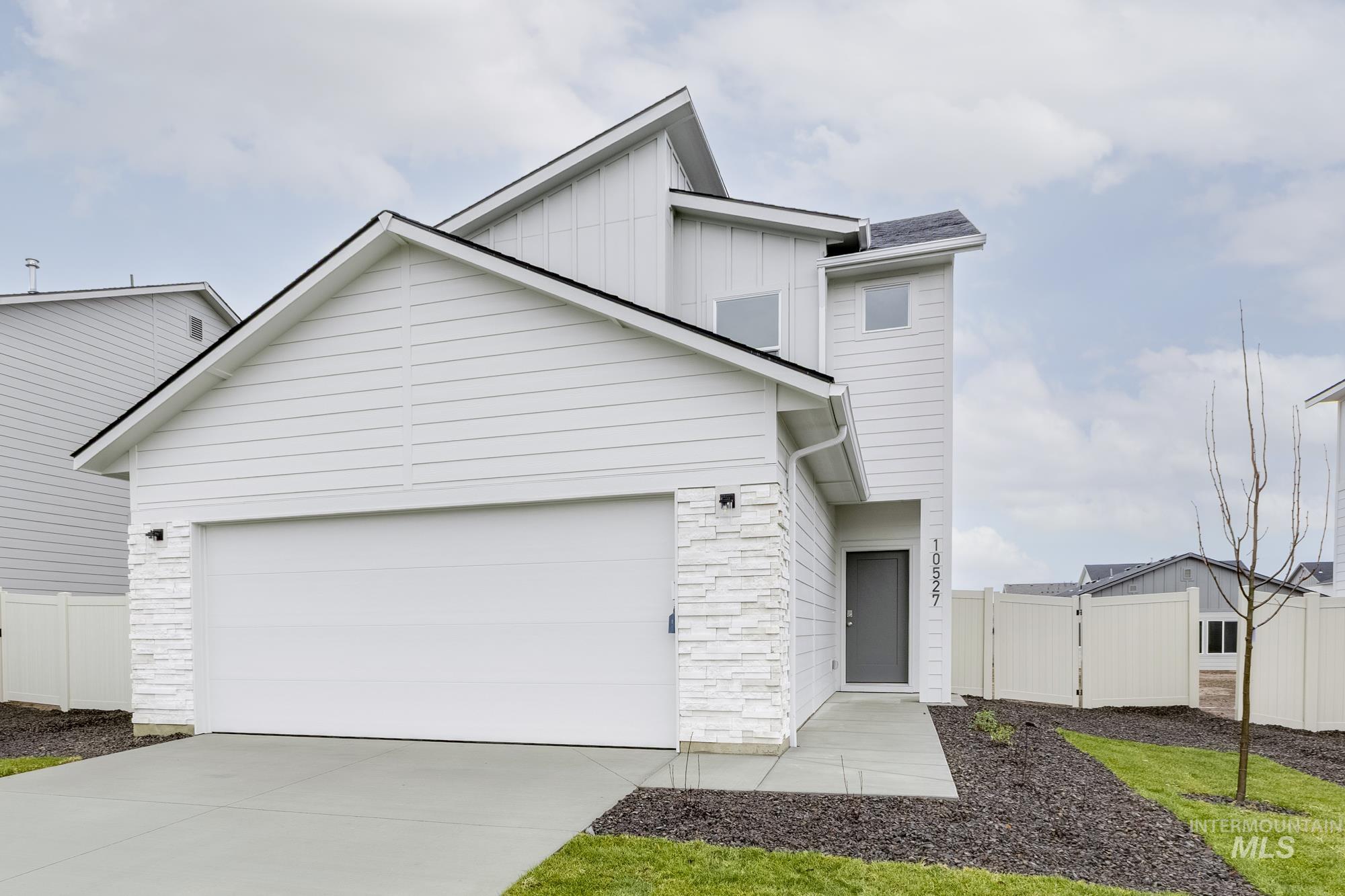 View of front of home featuring board and batten siding, stone siding, concrete driveway, and a garage