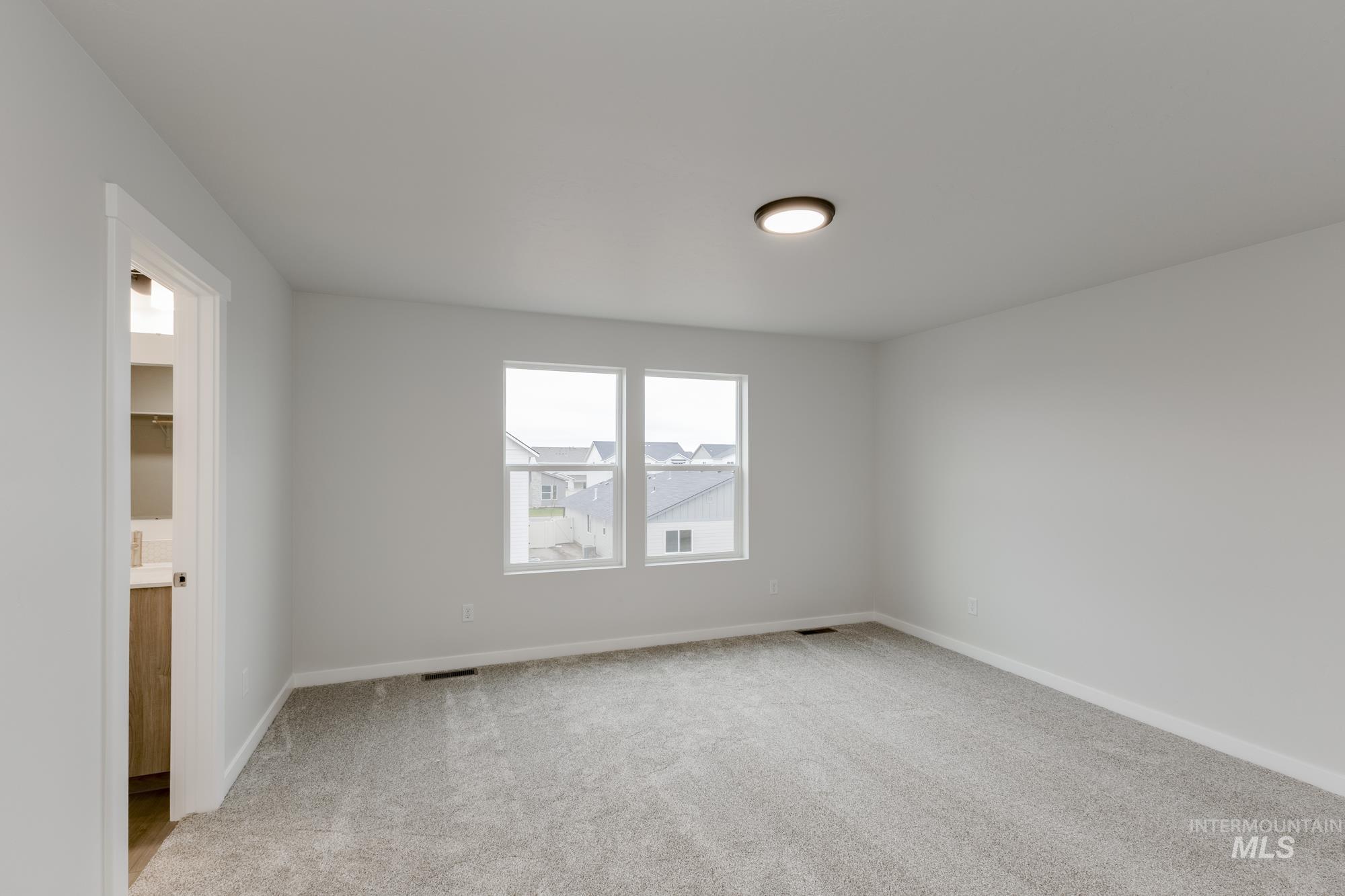 Spare room featuring light colored carpet and baseboards