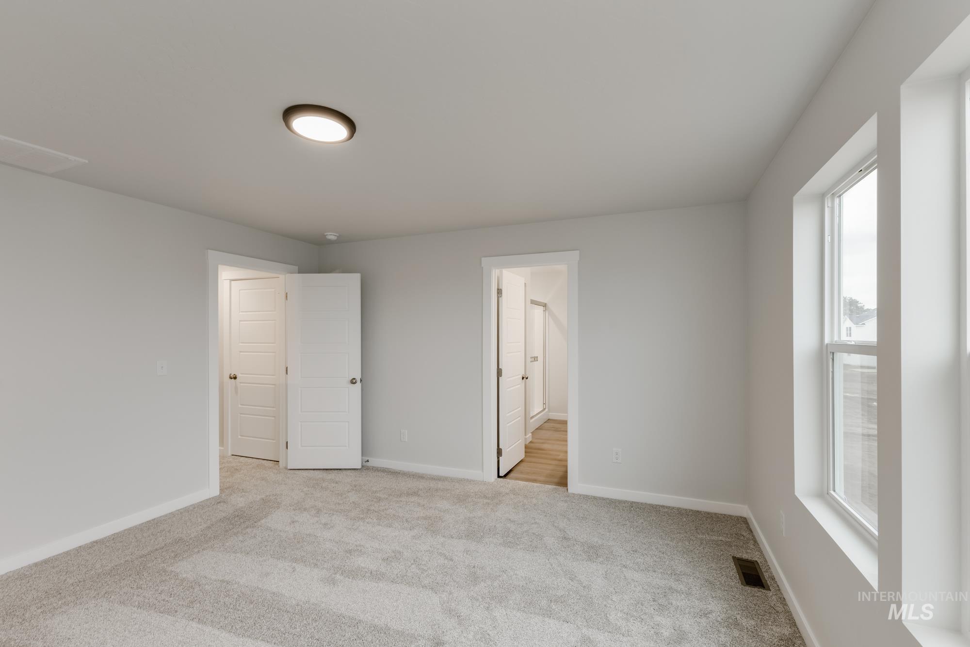 Unfurnished bedroom with light colored carpet and connected bathroom