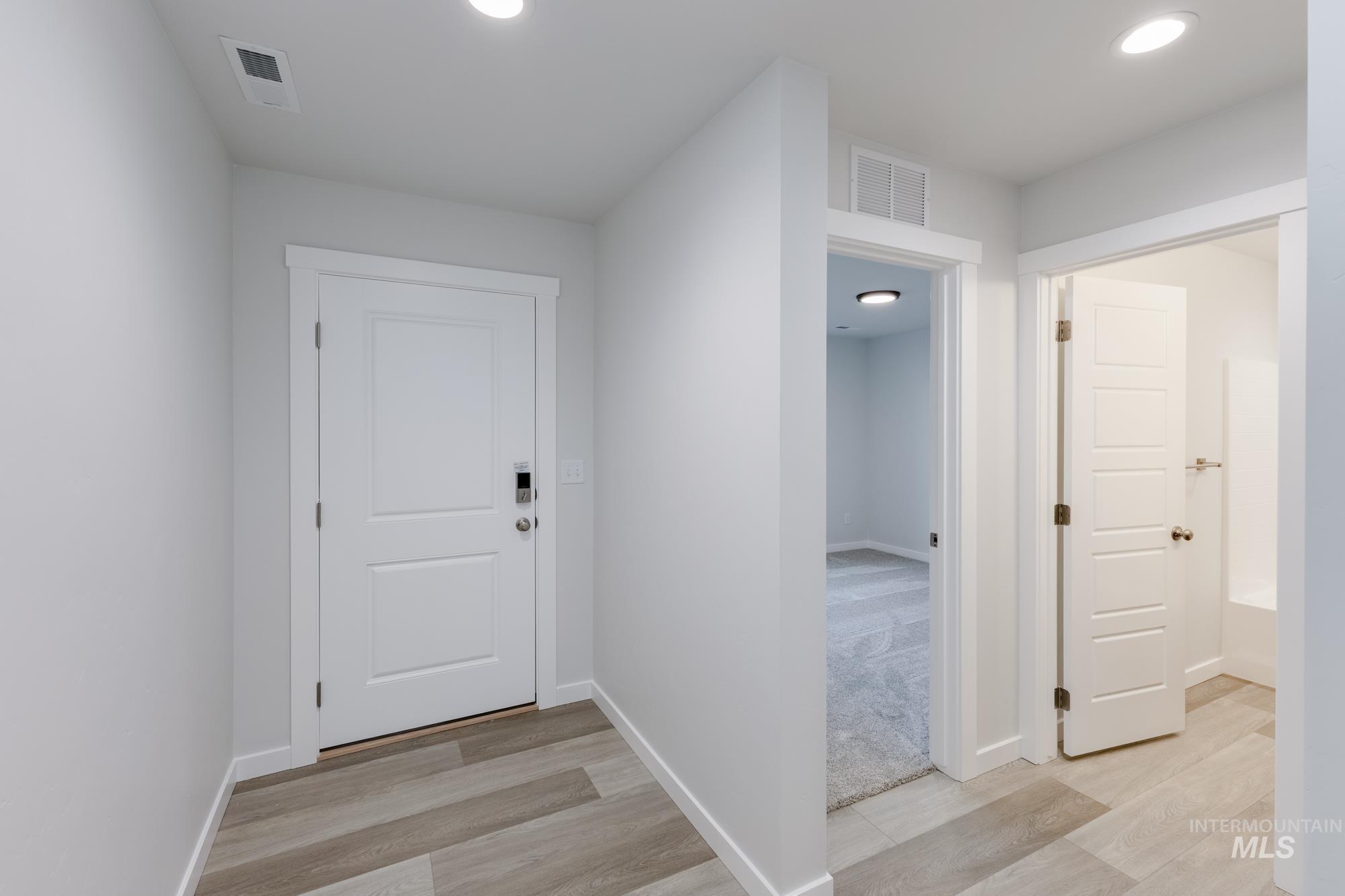 Doorway to outside with wood finished floors and recessed lighting