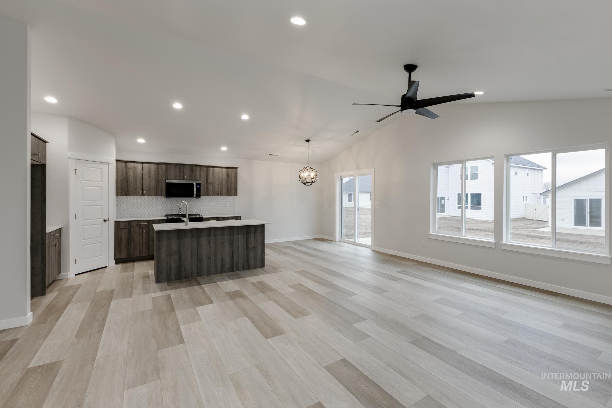 Kitchen with open floor plan, an island with sink, dark brown cabinetry, lofted ceiling, and recessed lighting