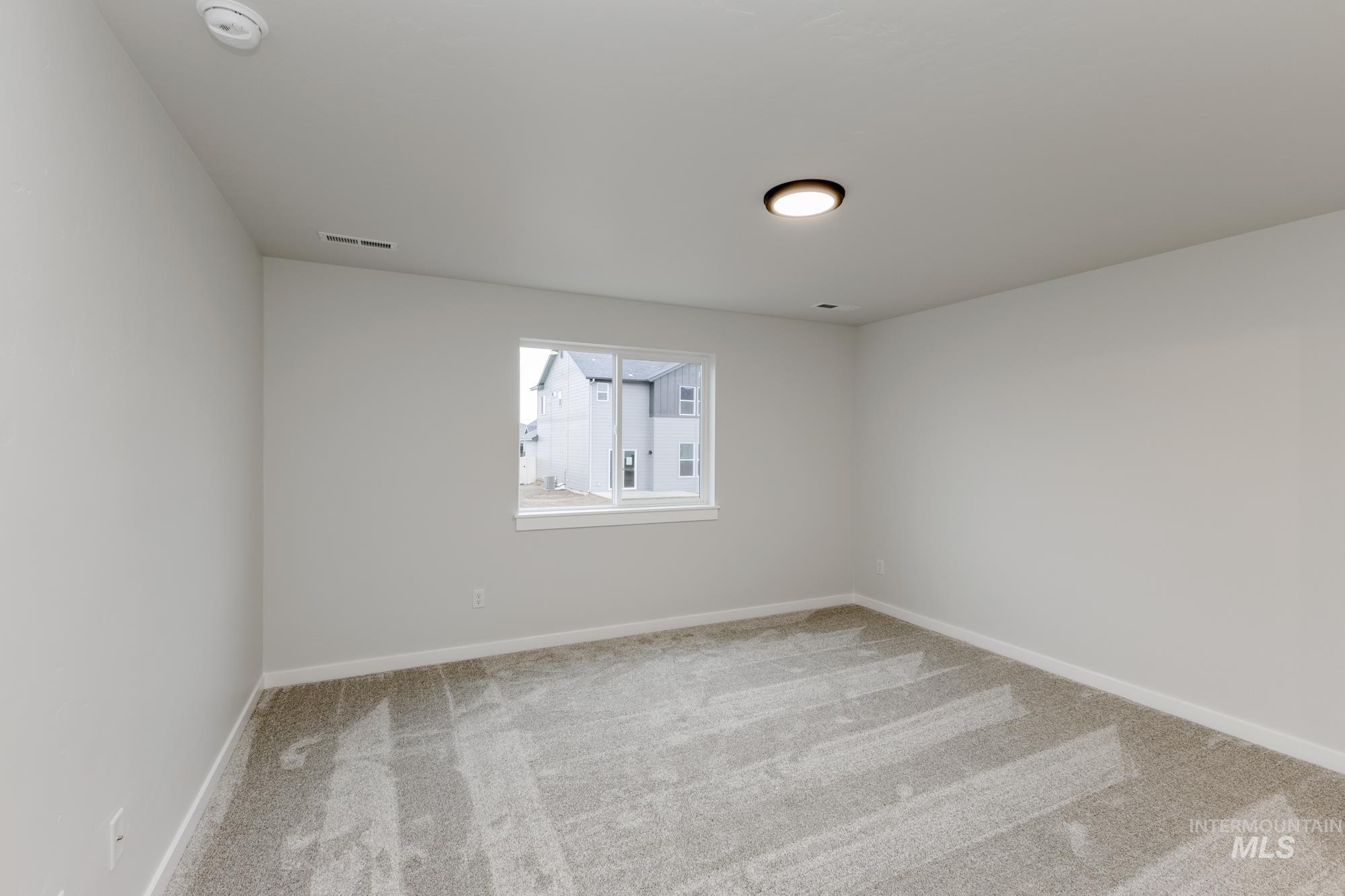 Spare room featuring light colored carpet and baseboards