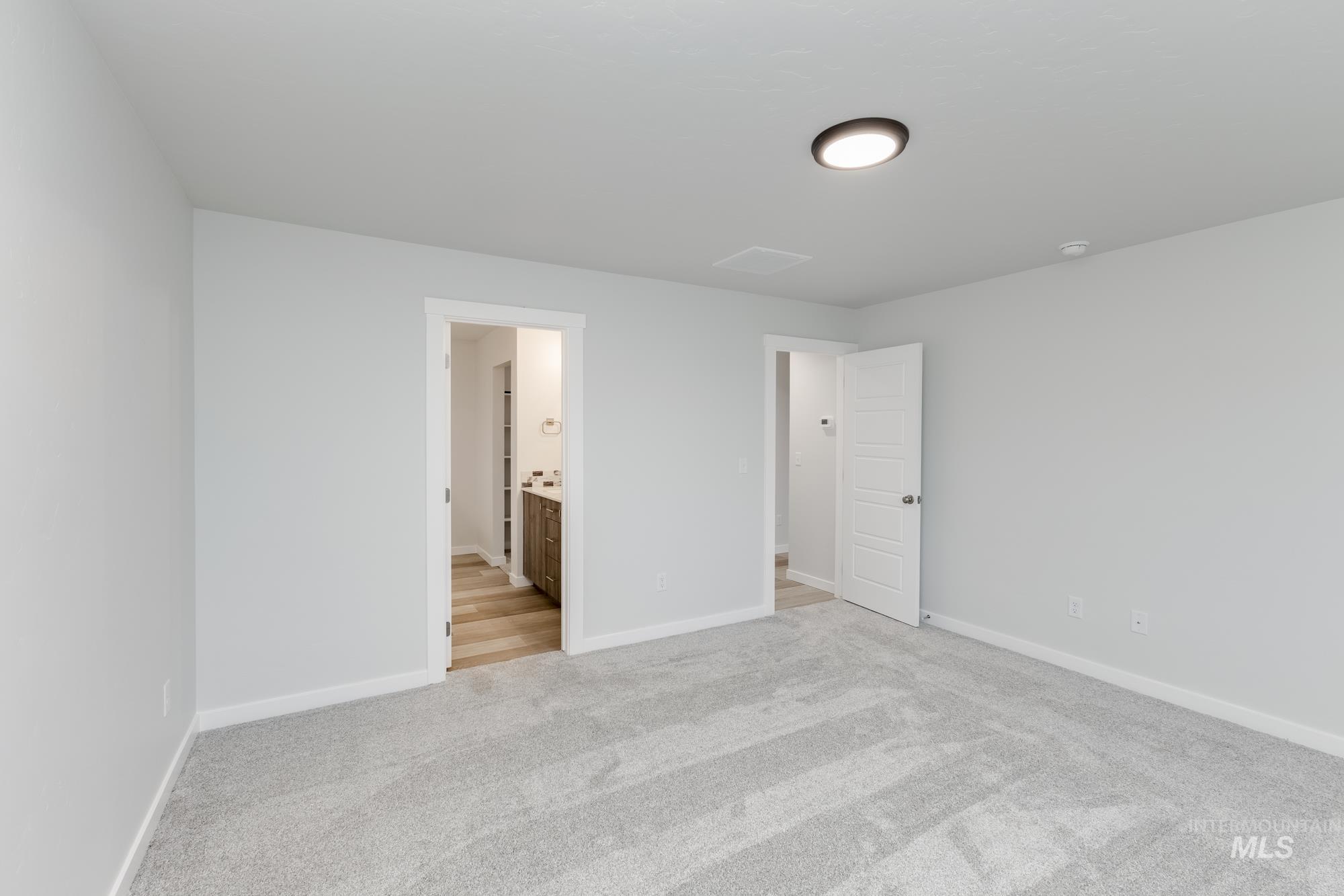 Unfurnished bedroom featuring light colored carpet and connected bathroom