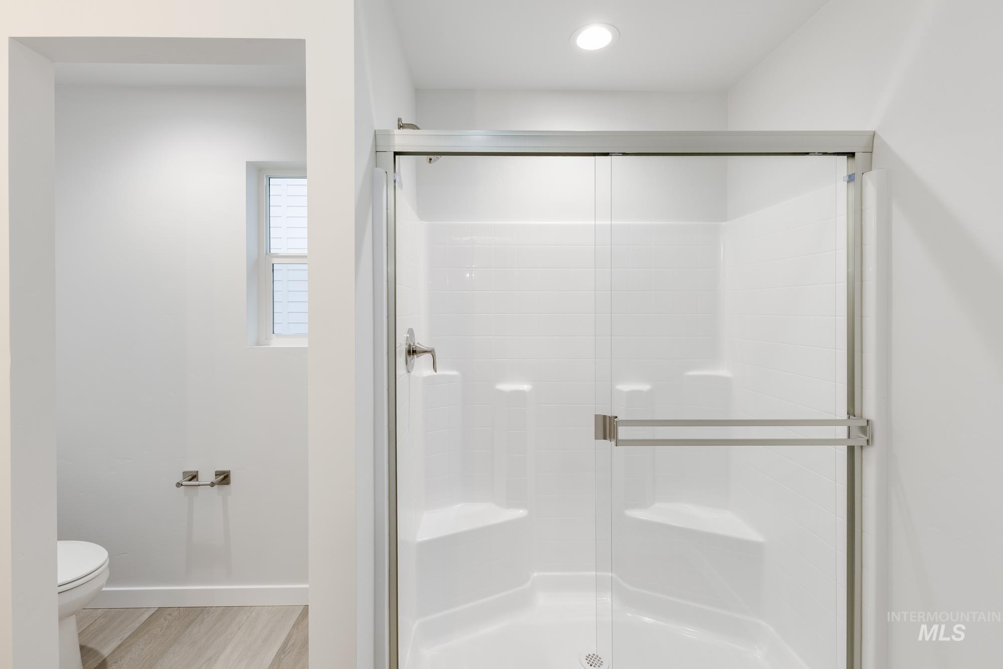 Bathroom with a shower stall and light wood finished floors