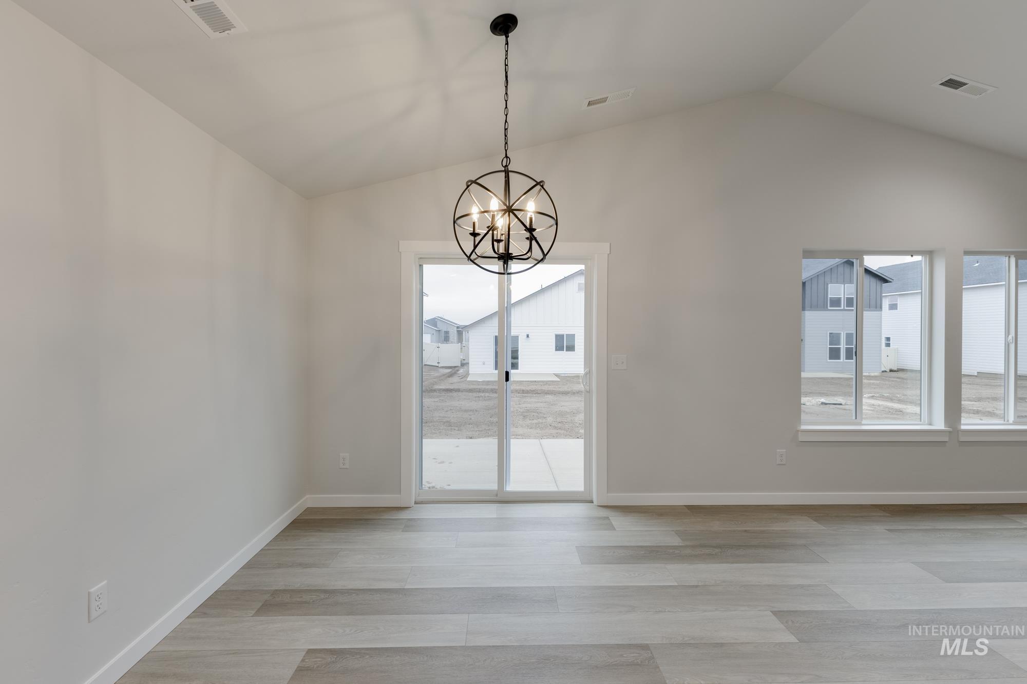 Unfurnished dining area featuring lofted ceiling, a chandelier, and light wood finished floors