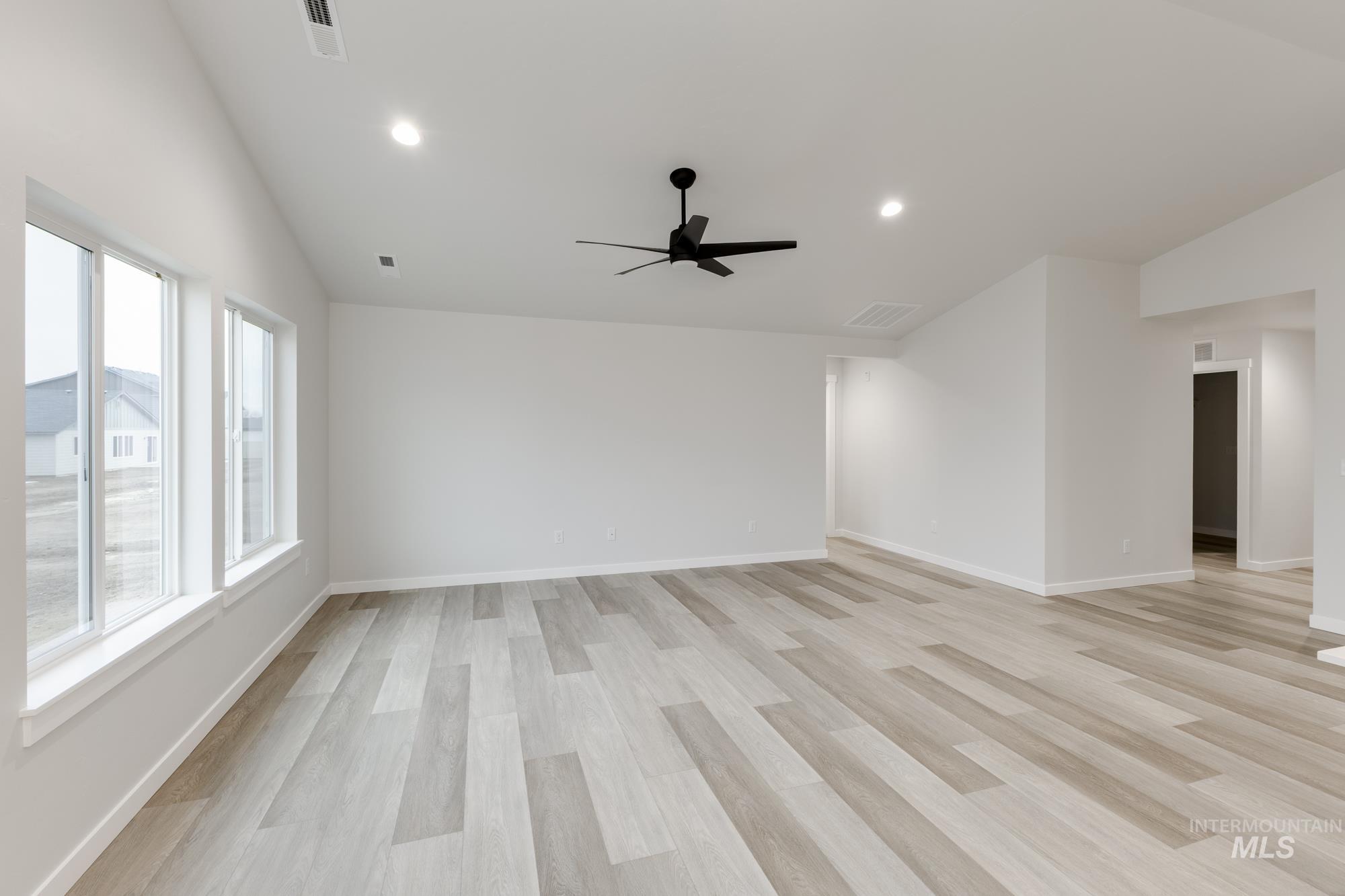 Empty room featuring vaulted ceiling, light wood-type flooring, recessed lighting, and a ceiling fan