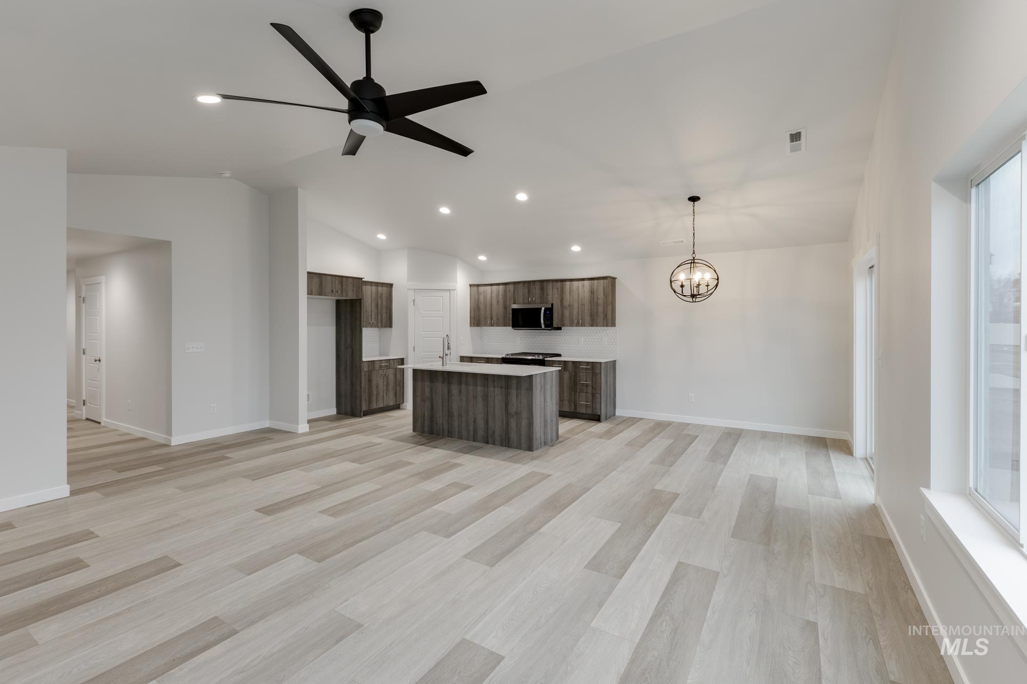 Kitchen featuring open floor plan, light countertops, lofted ceiling, a center island with sink, and modern cabinets