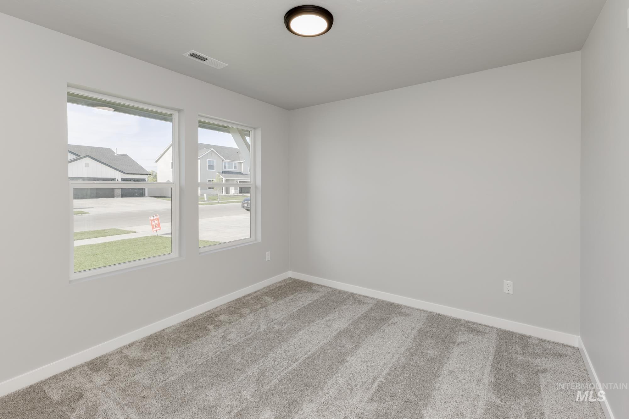 Carpeted spare room featuring baseboards
