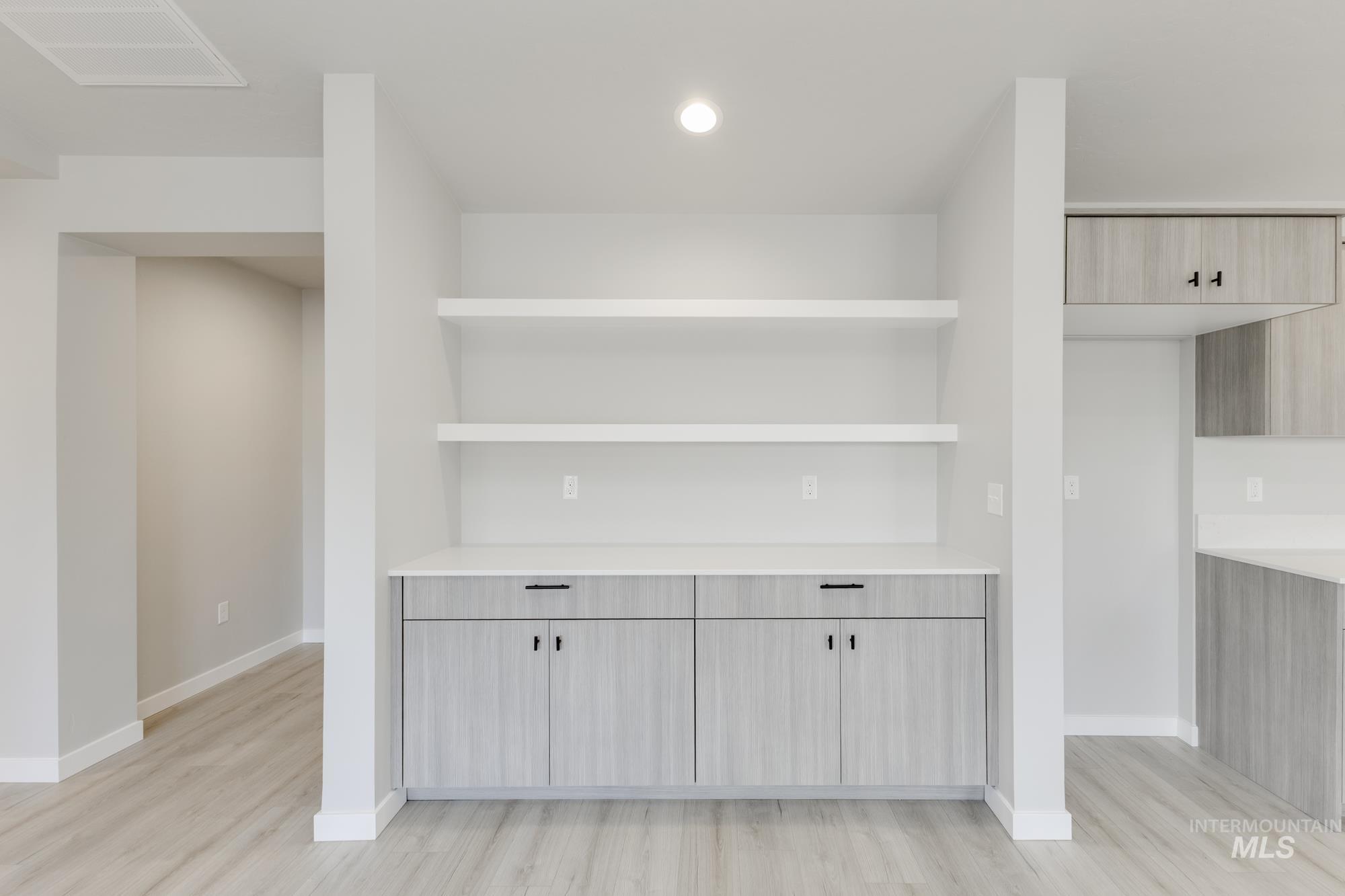 Bar area with open shelves, modern cabinets, light wood-style floors, and recessed lighting