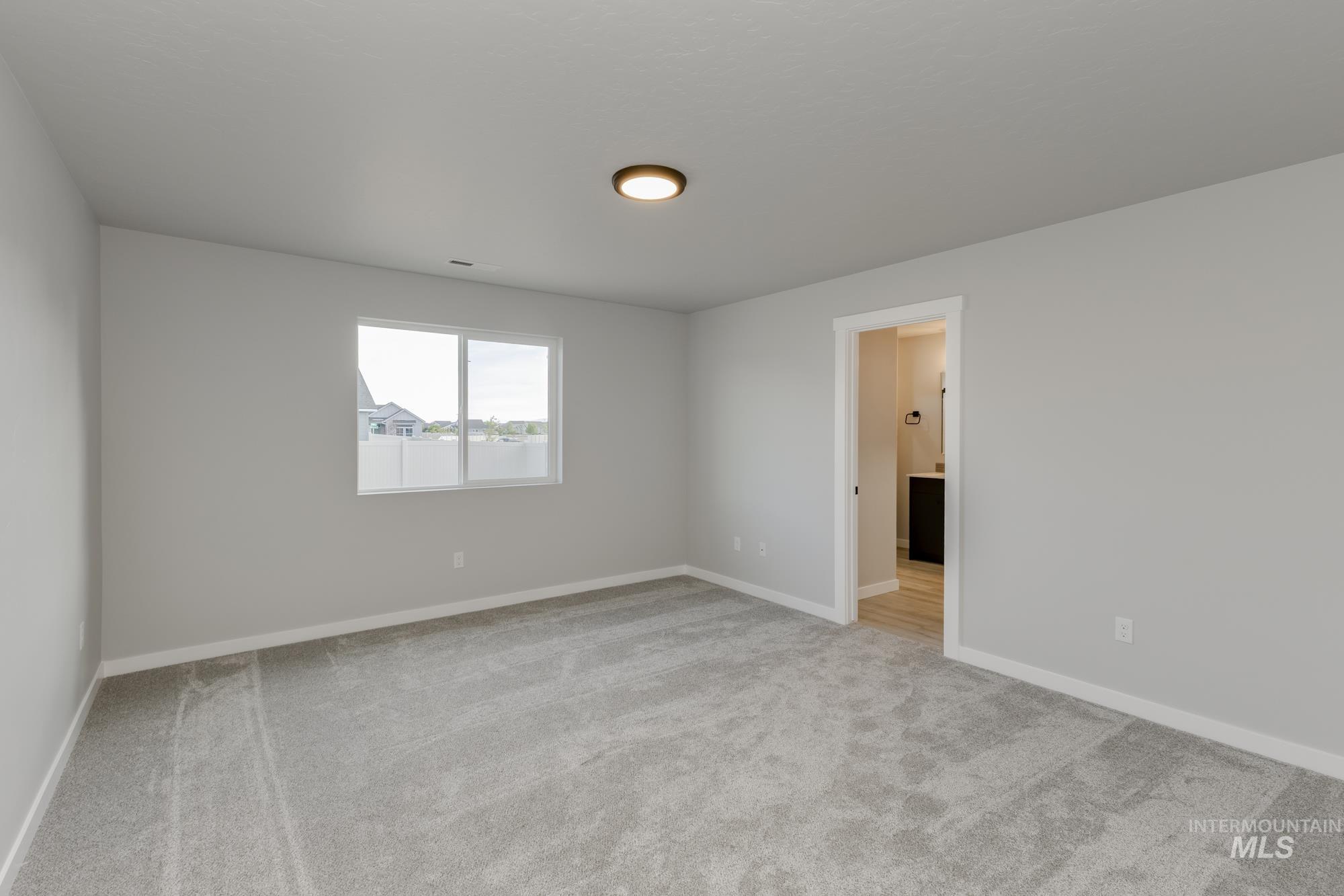 Empty room featuring light carpet and baseboards