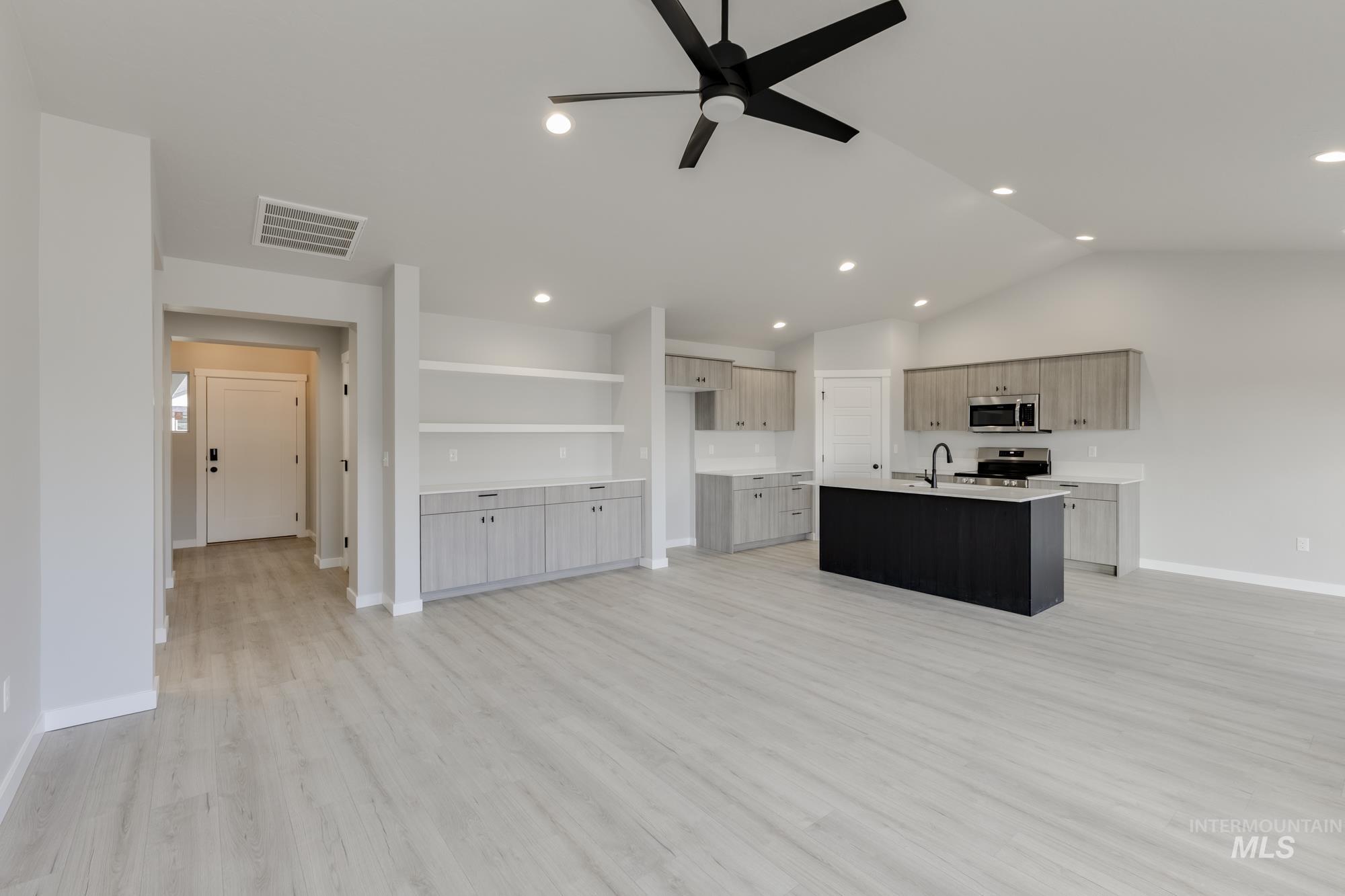 Kitchen featuring a ceiling fan, a kitchen island with sink, light wood-type flooring, appliances with stainless steel finishes, and open floor plan