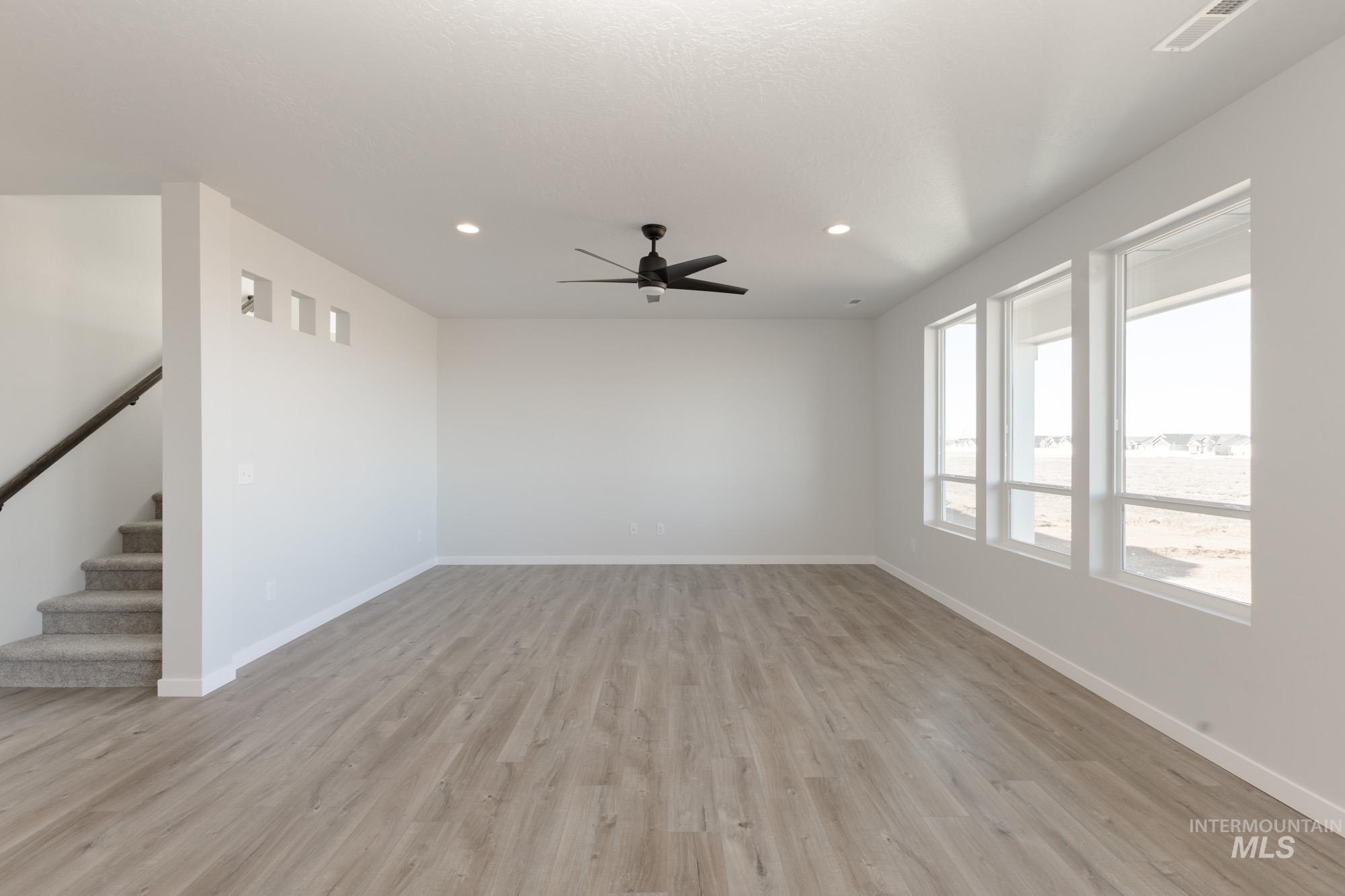 Empty room with light wood finished floors, recessed lighting, a ceiling fan, and stairway