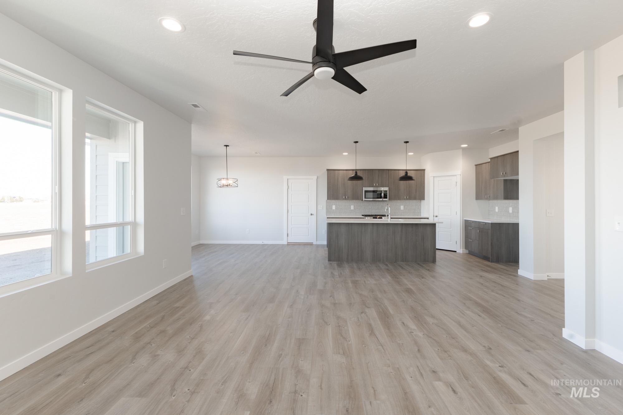 Unfurnished living room with a ceiling fan, light wood-type flooring, recessed lighting, and a chandelier