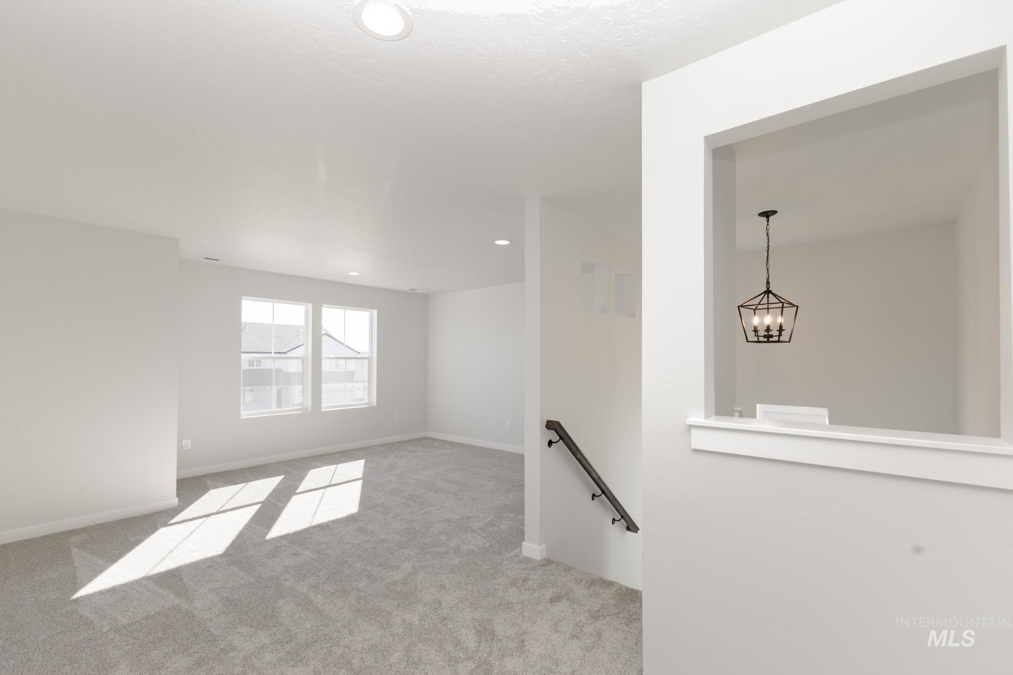 Unfurnished room featuring light colored carpet, recessed lighting, and a chandelier