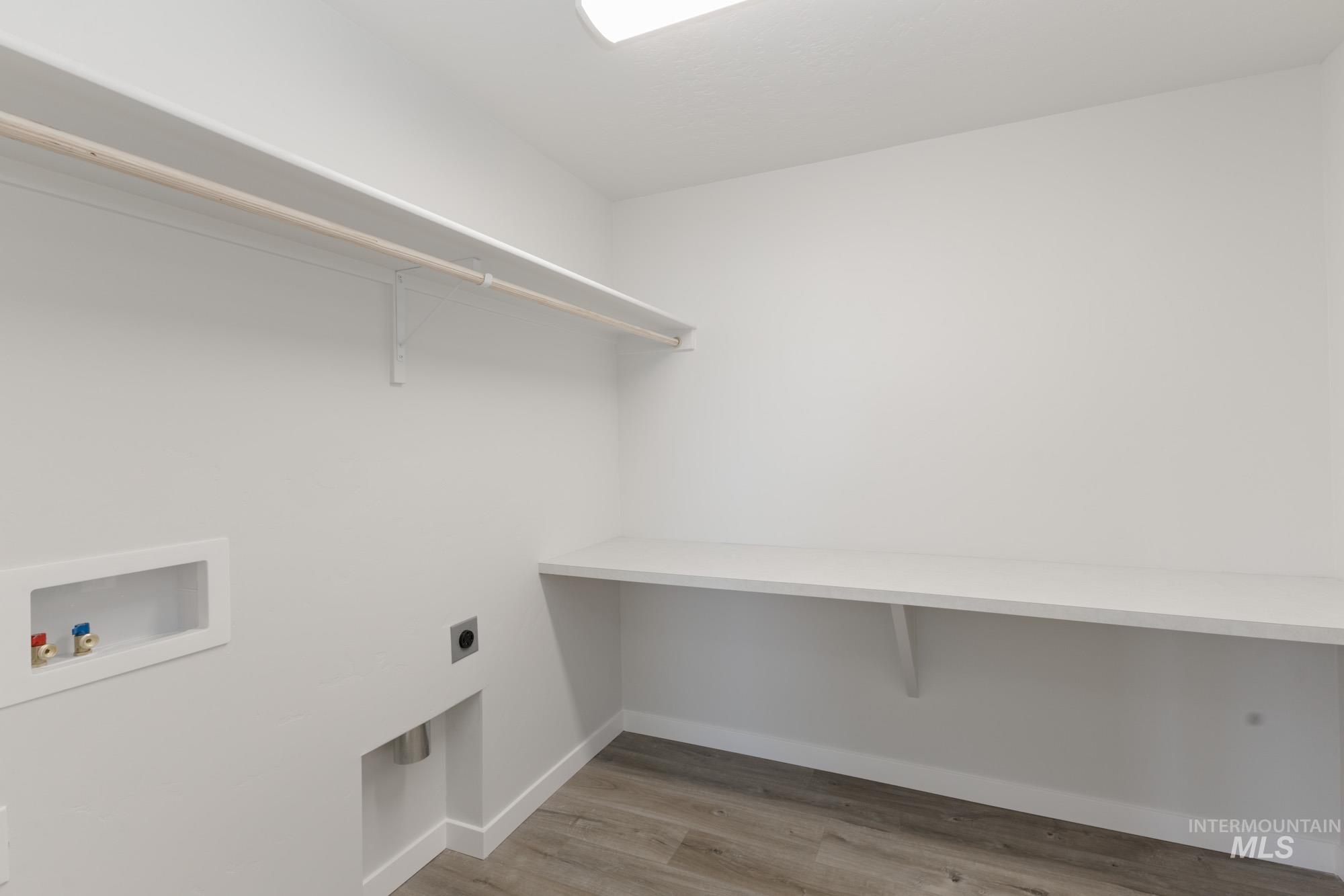 Laundry area with light wood-style flooring, hookup for a washing machine, and electric dryer hookup