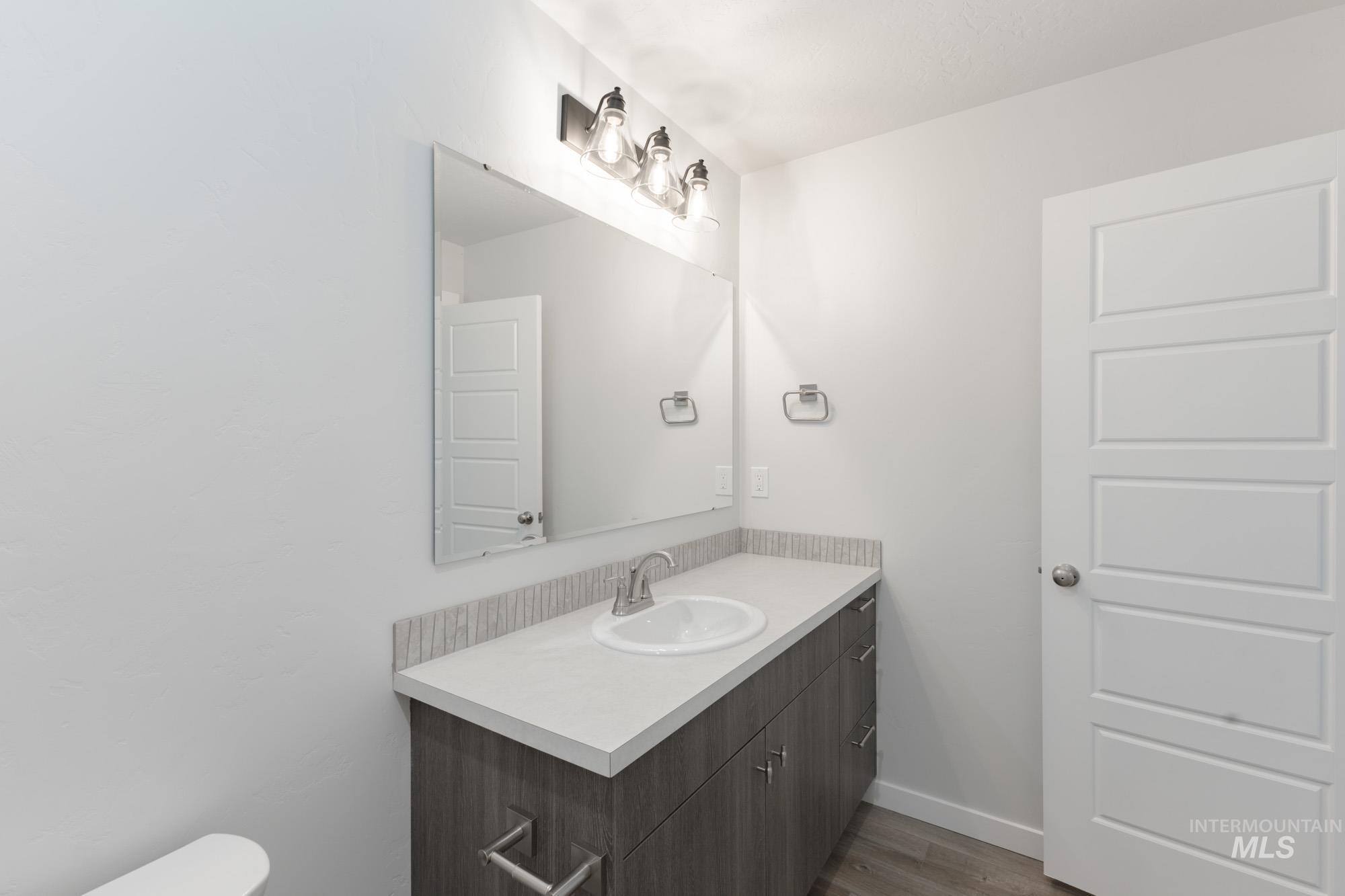 Half bathroom featuring vanity and dark wood finished floors