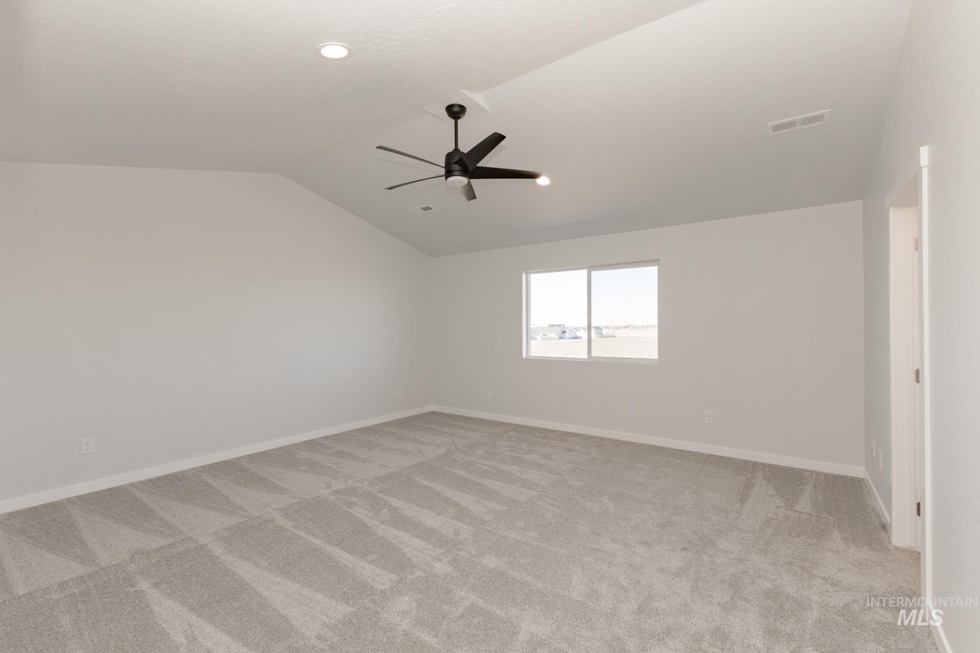 Bonus room with lofted ceiling, light carpet, and a ceiling fan