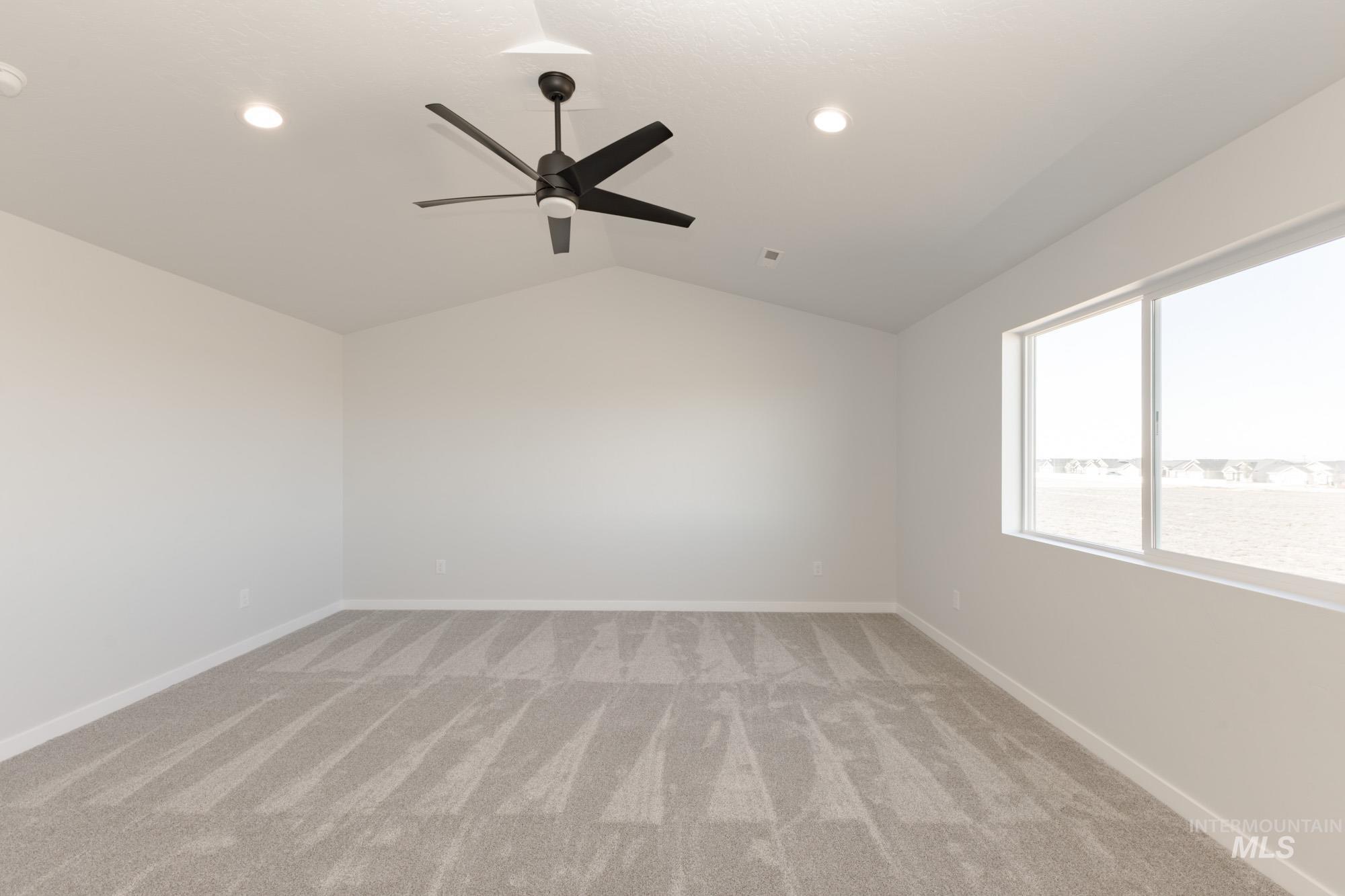 Spare room featuring lofted ceiling, light colored carpet, ceiling fan, and recessed lighting